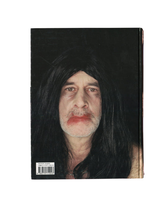 Reverse of 2001 Olaf Breuning Ugly, Hatje Cantz — hardcover back showing full-bleed colour photograph of a shirtless young man in aviator sunglasses and black wig covered in temporary tattoos including a large tiger on the abdomen, holding a Gatorade bottle, standing outdoors against a rocky background in red Champion shorts