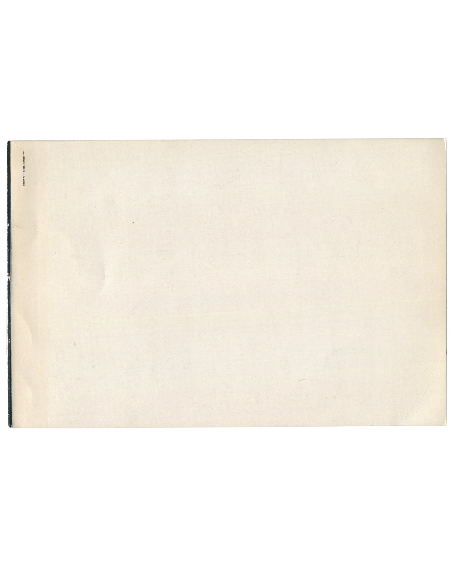 Reverse of c.1960s Madeleine Alain Brieux Collages Galerie du Passeur Paris exhibition invitation card showing near-blank cream-white card stock with warm age toning, light surface marks, and faint vertical fold line at left; small black text at far left edge reading 'IMPRIMERIE FIRMIN-DIDOT' in tiny type; staple binding visible at le