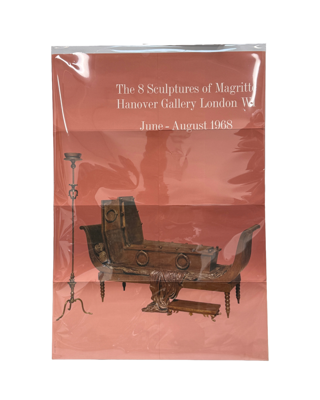 Original 1968 René Magritte The 8 Sculptures of Magritte Hanover Gallery London exhibition poster, offset print on thin stock in terracotta-rose ground, shown in original protective plastic sleeve with visible fold lines; white italic serif text at upper centre reading 'The 8 Sculptures of Magritte / Hanover Gallery London W1 / June – August 1968'; lower two-thirds showing a colour photograph of two Magritte sculptures against the rose ground: at left, a tall ornate wrought-iron floor candlestick with tripo