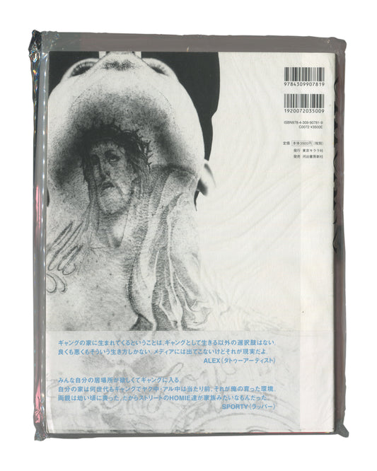 Photobook back cover with obi, Keisuke Nagoshi, CHICANO, Tokyo Kirara-sha / Kawade Shobo Shinsha, Japan, 2008. Sealed in original distributor shrinkwrap. Full-bleed black-and-white photograph — continuation of tattooed torso image from front cover. Upper right: two barcodes and publisher details — 'ISBN978-4-309-90781-9 / C0072 ¥3500E / 発行 東京キララ社 / 発売 河出書房新社'. Lower third: obi with two Japanese text quotations attributed to ALEX (tattoo artist) and SPORTY (rapper). Shrinkwrap shows light surface rubbing