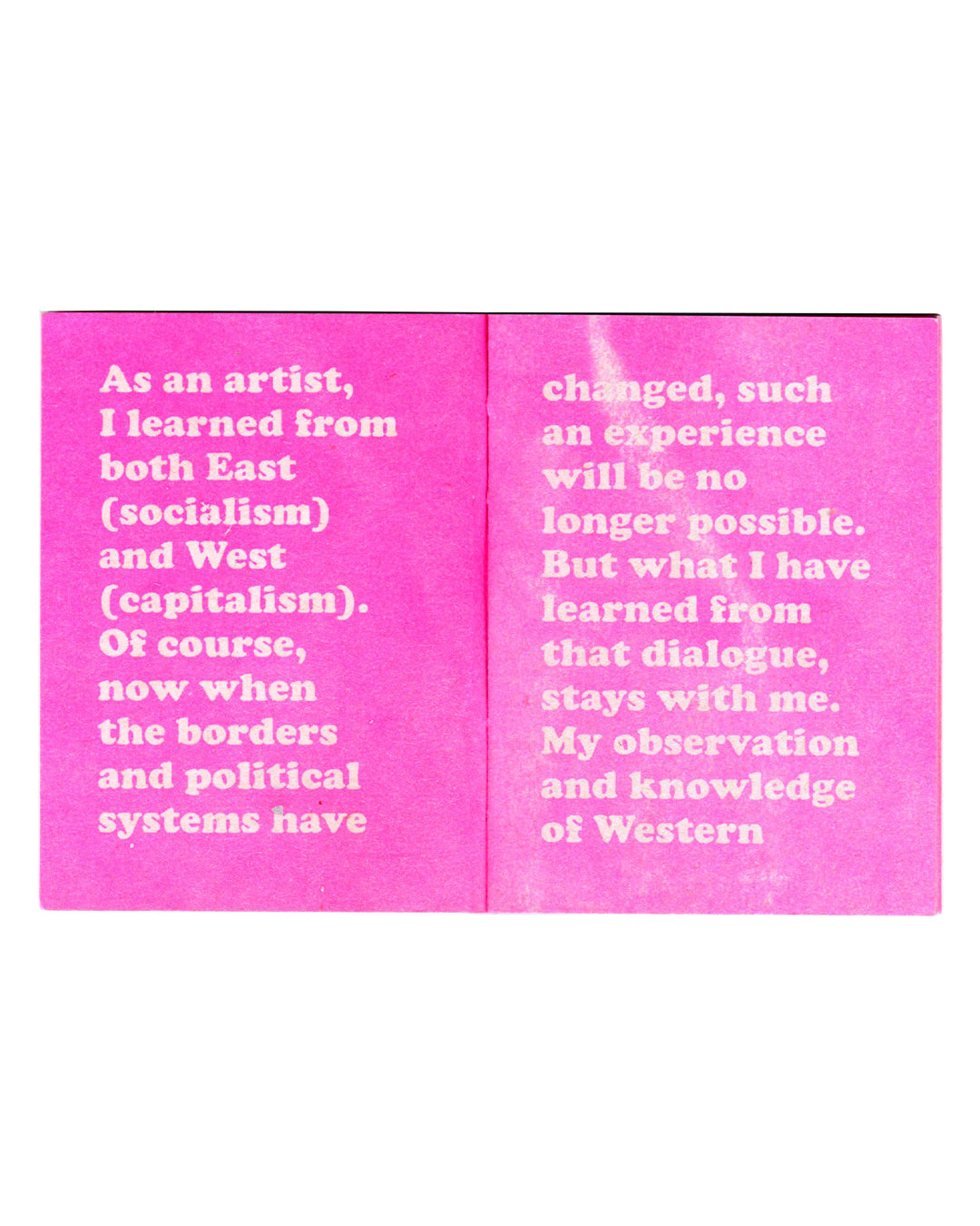 Interior spread of Mladen Stilinović, The Praise of Laziness, Gato Negro, 2015, showing pale pink sans-serif text on magenta pages reading "As an artist, I learned from both East (socialism) and West (capitalism). Of course, now when the borders and political systems have" on the left and "changed, such an experience will be no longer possible. But what I have learned from that dialogue, stays with me. My observation and knowledge of Western" on the right.