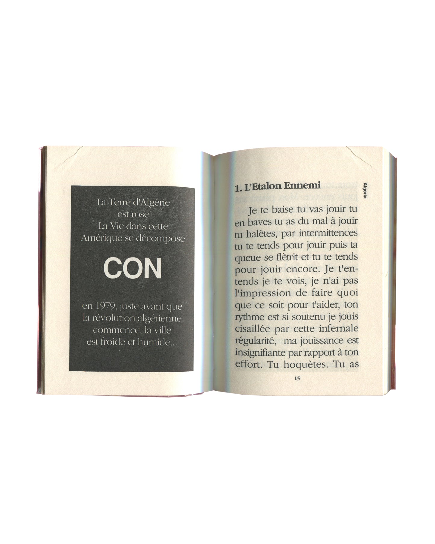 nterior spread of 1988 Kathy Acker Algeria French edition — left page: black panel with white text reading La Terre d'Algérie est rose / La Vie dans cette Amérique se décompose / CON / en 1979, juste avant que la révolution algérienne commence, la ville est froide et humide…; right page: chapter heading 1. L'Etalon Ennemi with opening prose text in French in serif body type; page 15 visible at foot; Algeria running head at upper right.