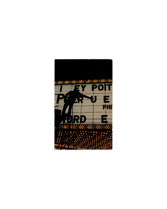 Recto — George Segal photograph Photonotations, Rosa Esman Gallery, New York, 1976. Exhibition invitation recto: colour photograph by George Segal — a figure in silhouette stands on a ladder or platform working across an illuminated theatre marquee at night, partially obscuring large black letters on a white backlit sign reading fragments "I EY POIT", "P…RUE", "PHI", "ORD E"; rows of amber and gold bulbs border the sign above and below; dark sky above. 14 × 9 cm.