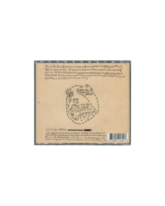 Reverse of 2004 Devendra Banhart Rejoicing in the Hands CD — cream back cover with hand-lettered track listing in cursive script, central oval illustration of a coiled figure with inset text, XL catalogue number XLCD180 and barcode at foot

