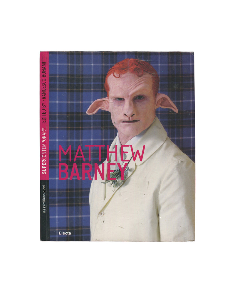 Original 2007 Matthew Barney Supercontemporary exhibition publication, Electa, Milan. Cover showing Barney in prosthetic makeup with pointed ears and pale skin, wearing a white suit jacket, set against a blue tartan background, with the title in magenta type and series name in a red vertical band.
