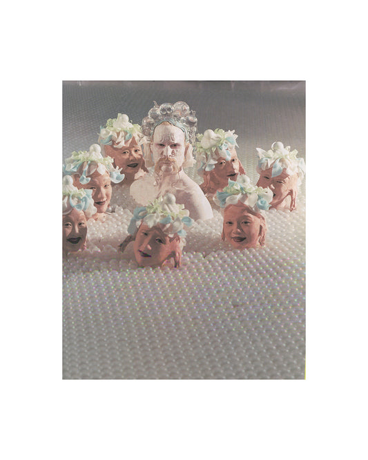 Interior page from 2007 Matthew Barney Supercontemporary, Electa. Showing a production photograph of multiple figures with elaborate floral and bubble headdresses submerged in a field of white pearled material, Barney at centre.