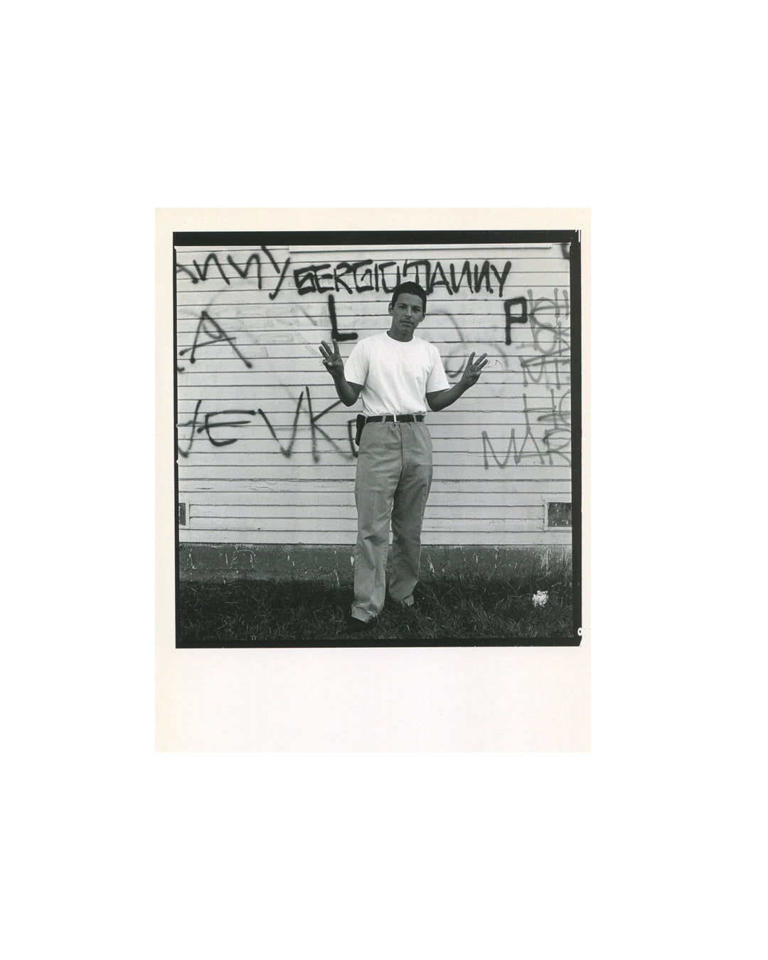 Interior spread showing black-bordered portrait of a young man in a white t-shirt standing before a graffiti wall reading SERGIO DANNY, hands raised with fingers spread.