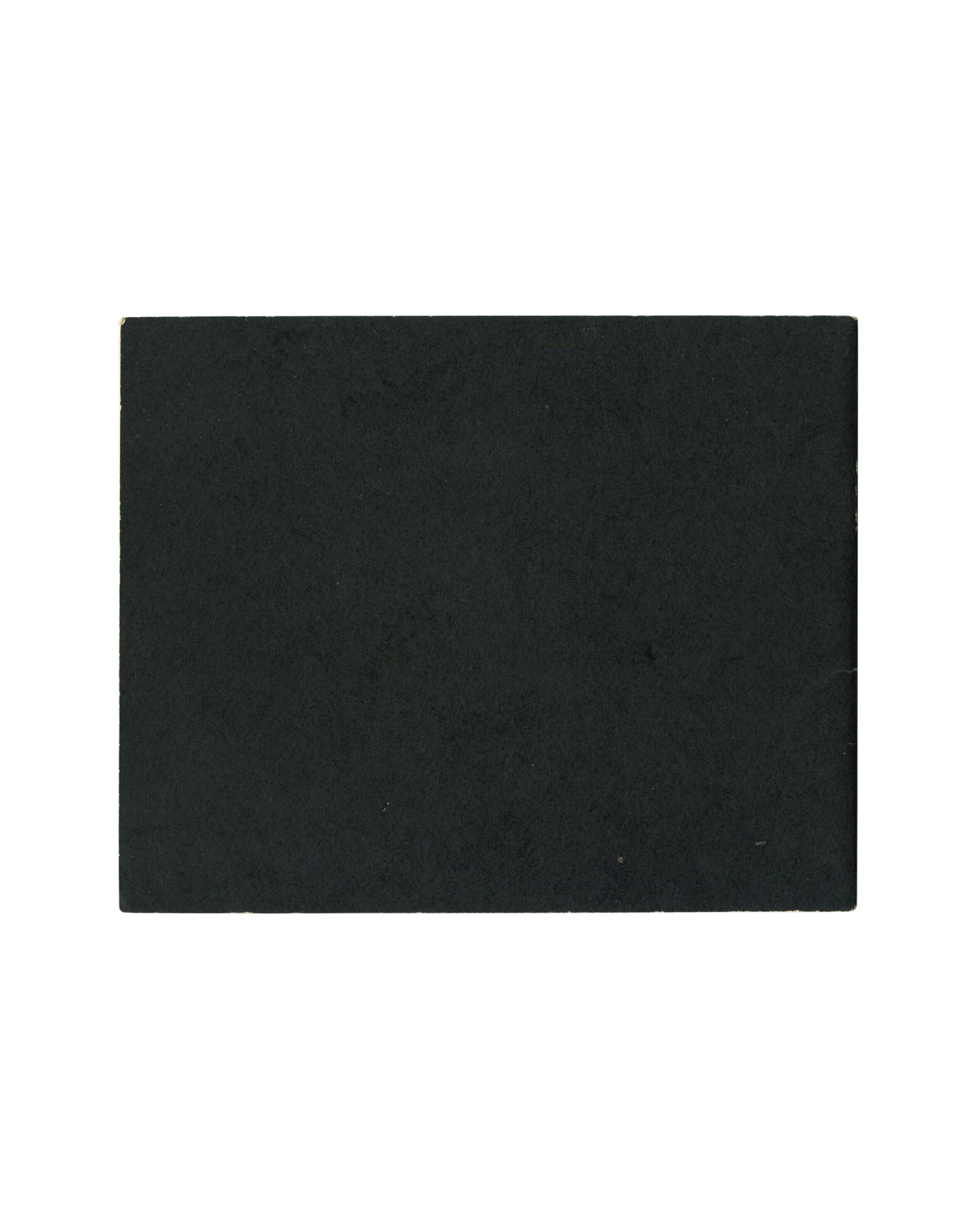 Plain black card with pronounced rubbing, scratching and edge wear. Saddle-stapled spine visible at left.