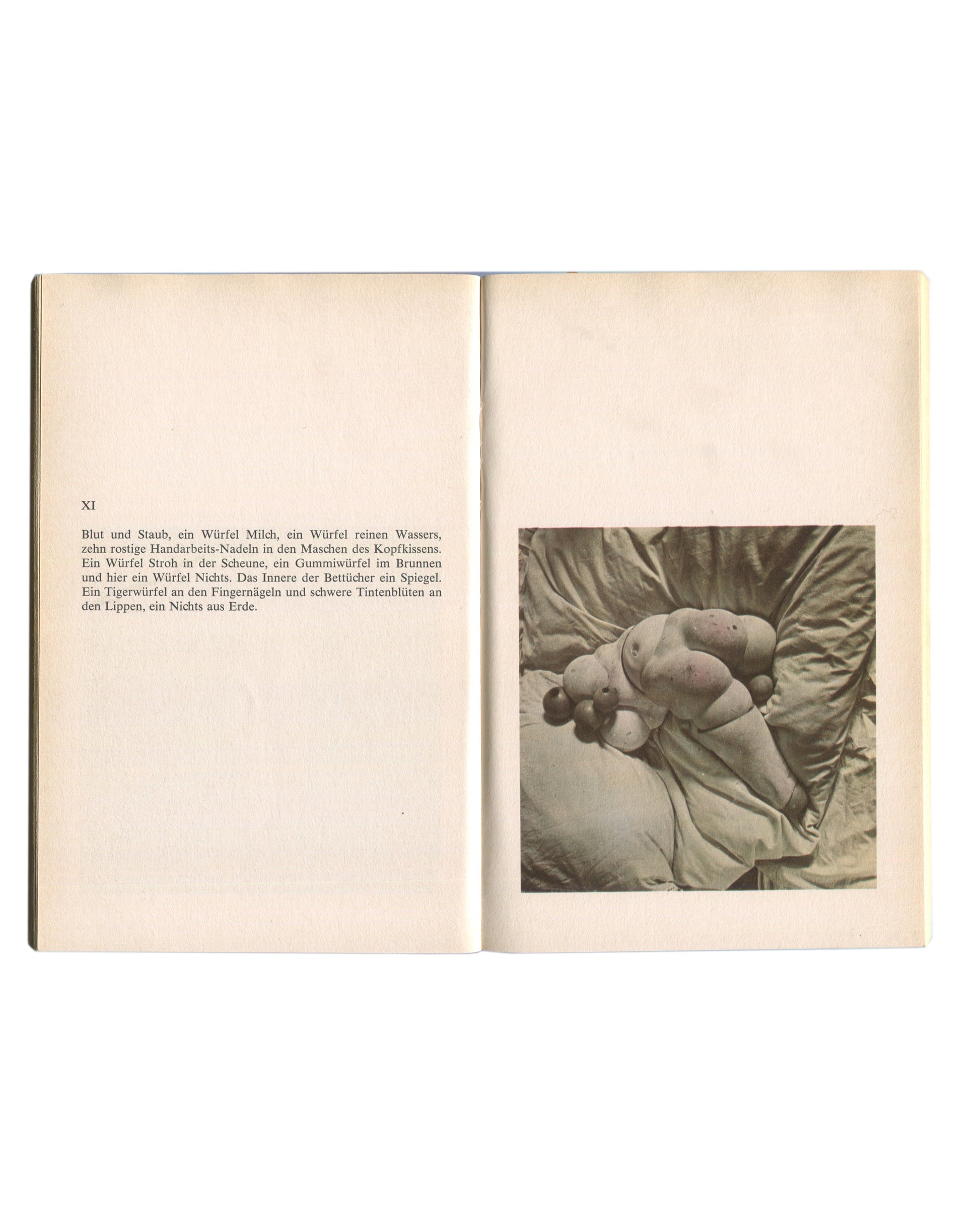 Interior spread of 1976 Hans Bellmer Die Puppe — left page with German prose text headed XI; right page with black-and-white photograph of a compact doll figure with multiple spherical body parts resting on satin fabric