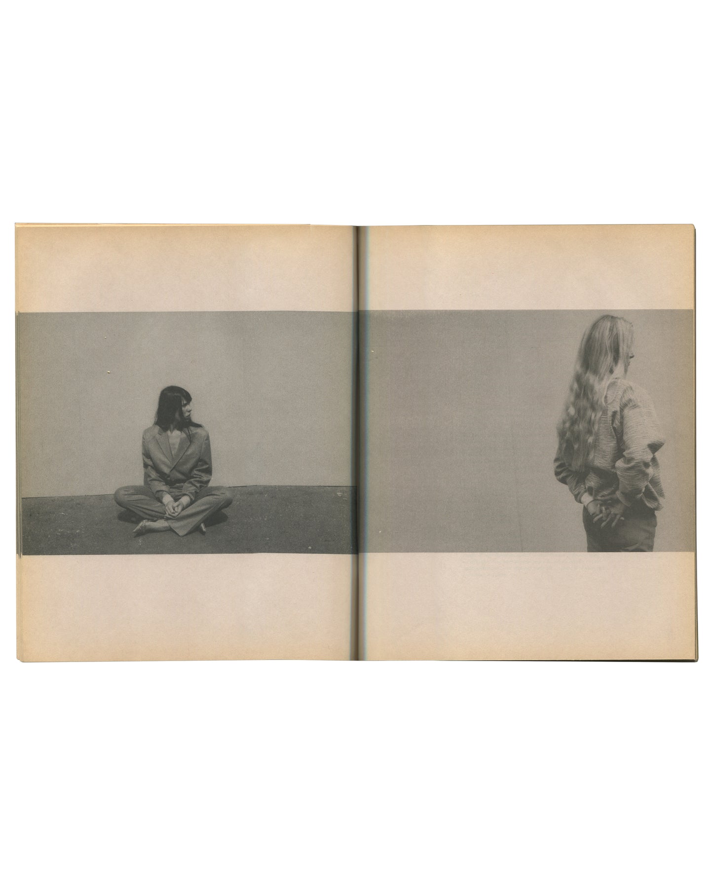 Interior spread of c. 2002 Mark Borthwick Social Documentaries Amid this Piste, self-published photocopy edition. Double-page spread showing two grayscale Xerox photographs printed as horizontal bands across tan-toned pages: left image showing a woman seated cross-legged on the floor against a plain wall, dark hair falling forward, wearing a dark suit, hands resting in her lap; right image showing a woman standing with her back to the camera, long loose hair falling to her waist, wearing a pale top with a d