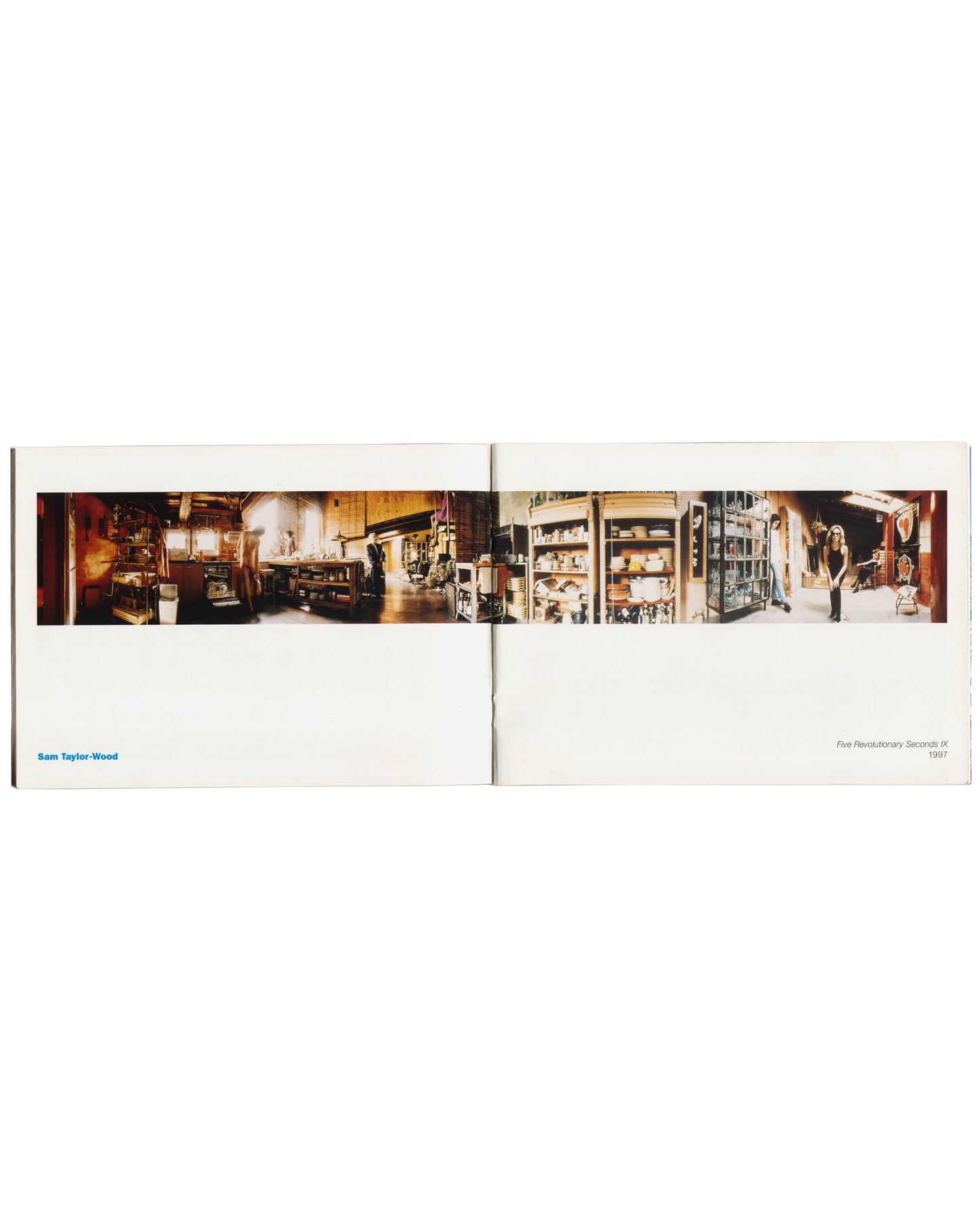Package Holiday, Hydra Workshop, 1997. Interior spread: Sam Taylor-Wood — Five Revolutionary Seconds IX, 1997, panoramic colour photograph extending across the full gutter — warm-toned studio interior with shelving, ceramics, equipment and a standing female figure visible right; "Sam Taylor-Wood" in blue lower left, title and date in small type lower right.