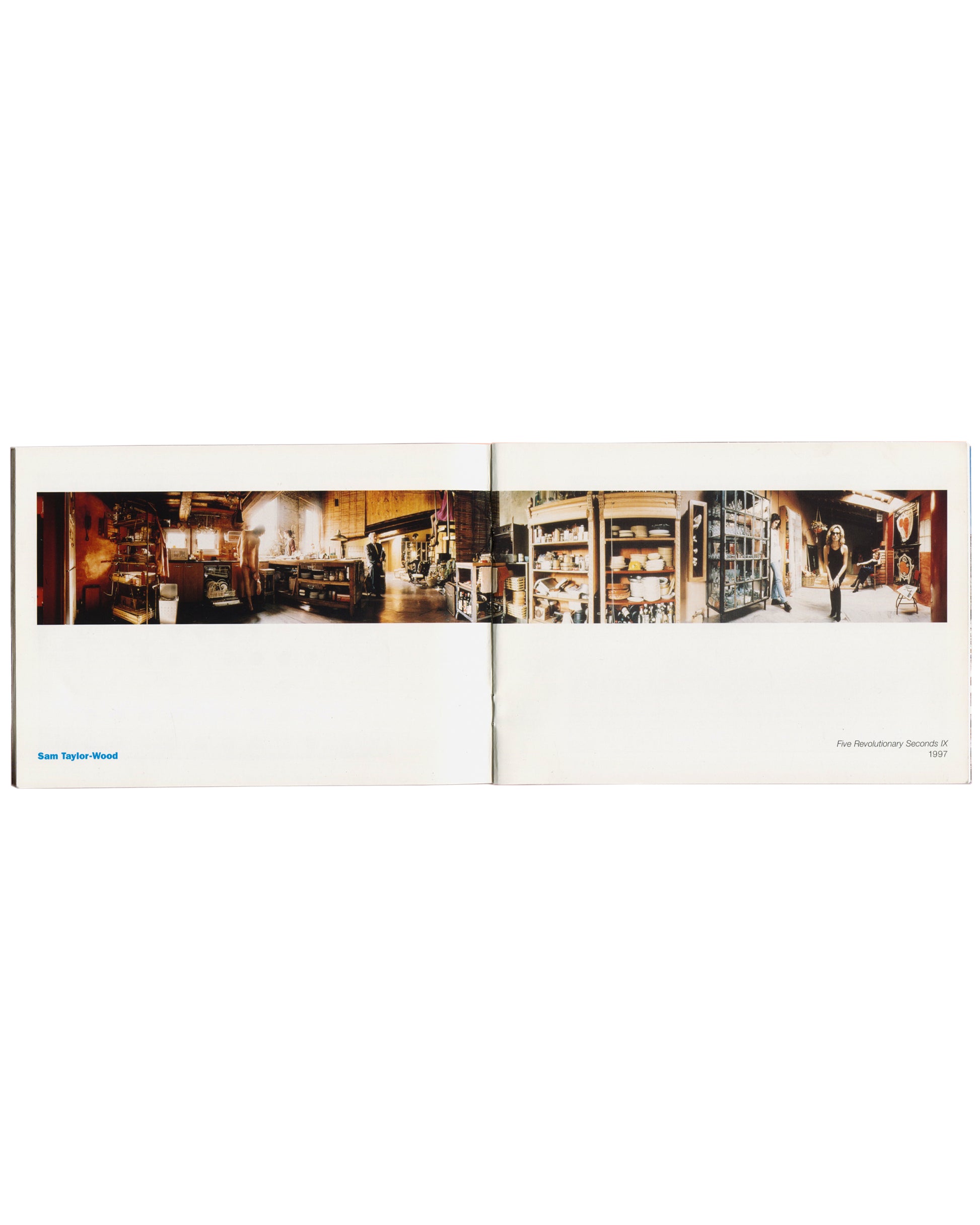 Package Holiday, Hydra Workshop, 1997. Interior spread: Sam Taylor-Wood — Five Revolutionary Seconds IX, 1997, panoramic colour photograph extending across the full gutter — warm-toned studio interior with shelving, ceramics, equipment and a standing female figure visible right; "Sam Taylor-Wood" in blue lower left, title and date in small type lower right.