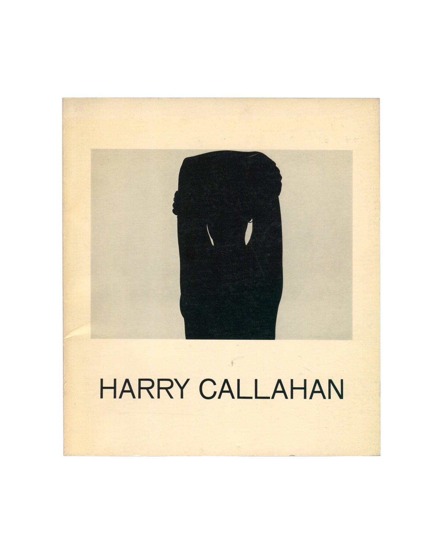 Original 1967 Harry Callahan exhibition catalogue, Museum of Modern Art, New York. Cream softcover with a black-and-white photograph of a standing female figure seen from behind, torso bare, seated on a stool before a window with venetian blinds, interior domestic space visible around her. 'HARRY CALLAHAN' in sans-serif type below the image.
