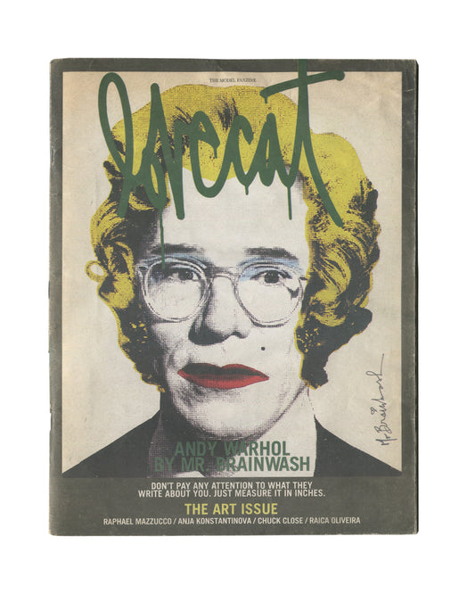 Second cover variant of 2012 Lovecat: The Model Fanzine, Issue 3, The Art Issue. Large black-and-white halftone portrait of Andy Warhol with yellow hair and red lips, overlaid with dark green graffiti-style 'lovecat' lettering and Mr. Brainwash signature at lower right. Caption reads 'ANDY WARHOL BY MR. BRAINWASH / THE ART ISSUE / DON'T PAY ANY ATTENTION TO WHAT THEY WRITE ABOUT YOU. JUST MEASURE IT IN INCHES.' Contributors listed: Raphael Mazzucco, Anja Konstantinova, Chuck Close, Raica Oliveira.