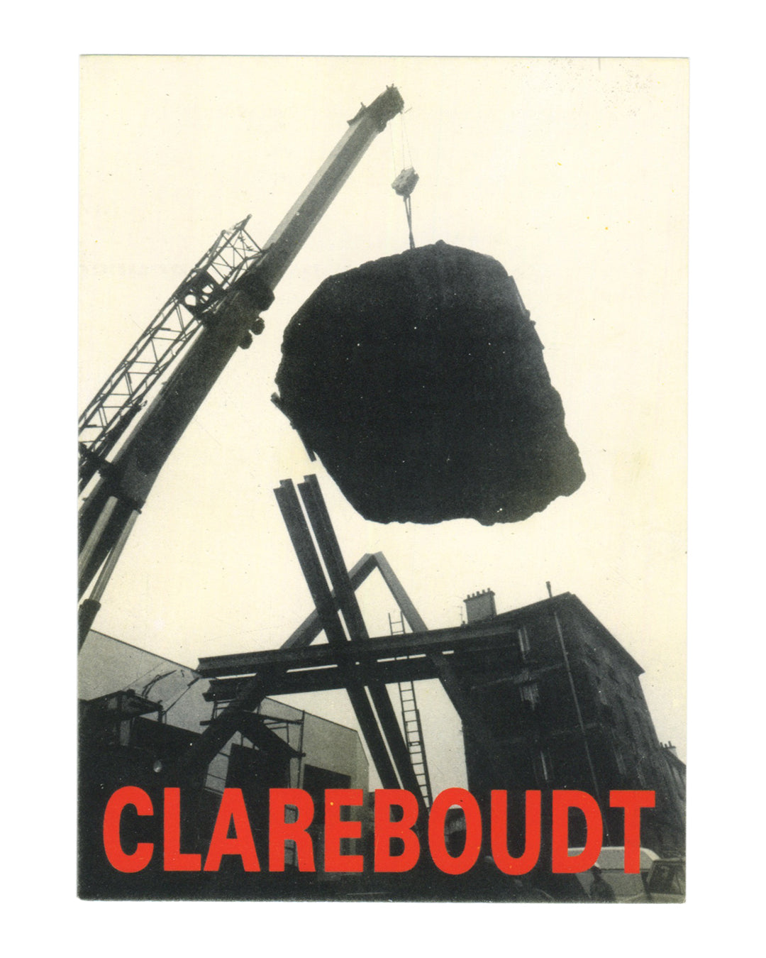 Jean Clareboudt, Oblique Haute, exhibition invitation recto. CREDAC Centre d'Art Contemporain, Galerie Fernand Léger, Ivry-sur-Seine, 1990. Black-and-white photograph: a large irregular dark mass — a boulder or raw stone — suspended from a crane arm against a pale overcast sky. The crane extends diagonally from the upper left; industrial steel structures, scaffolding, and a brick building are visible below and behind. Low-angle shot emphasising the weight and scale of the suspended object. 'CLAREBOUDT' in l