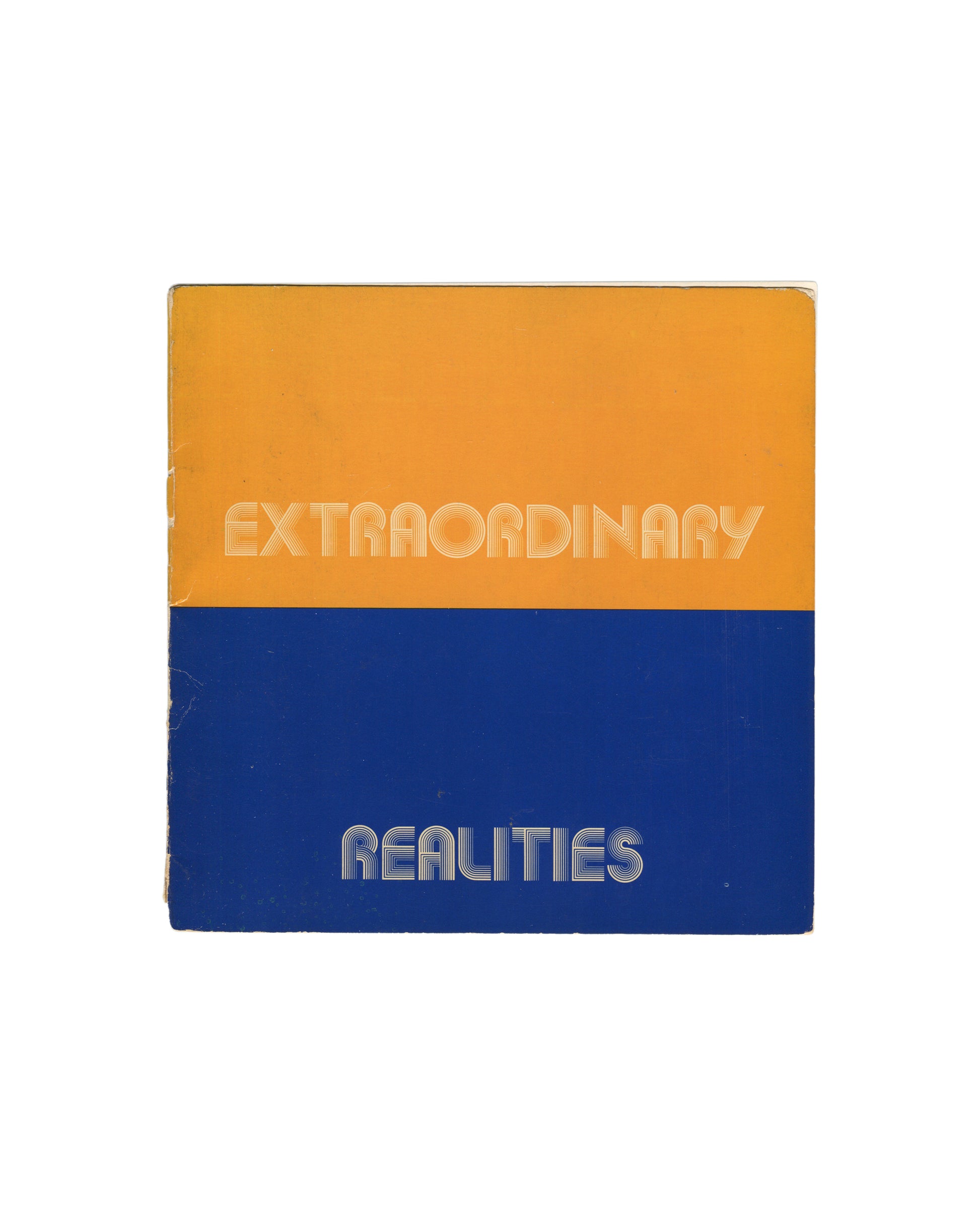 Original 1973 Robert Doty, Extraordinary Realities, Whitney Museum of American Art, New York. Square softcover divided horizontally into two equal bands — upper half in warm amber-orange, lower half in deep cobalt blue — with 'EXTRAORDINARY' in white outlined rounded sans-serif type on the orange field and 'REALITIES' in the same type on the blue field. Spine wear, edge rubbing, and corner creasing consistent with period."