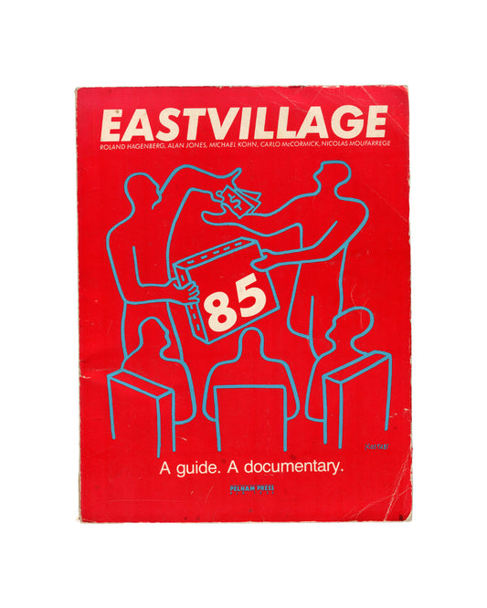 East Village '85: A Guide. A Documentary, Roland Hagenberg et al., Pelham Press, New York, 1985. Front cover. Solid red ground. Cream outline illustration by Mark Kostabi: five schematic figures seated and standing around a table, two figures exchanging a rectangular object labelled '85'. Title in large cream block capitals: 'EASTVILLAGE'. Below in smaller type: 'Roland Hagenberg, Alan Jones, Michael Kohn, Carlo McCormick, Nicolas Moufarrege'. Lower centre: 'A guide. A documentary.' Publisher: Pelham Press.