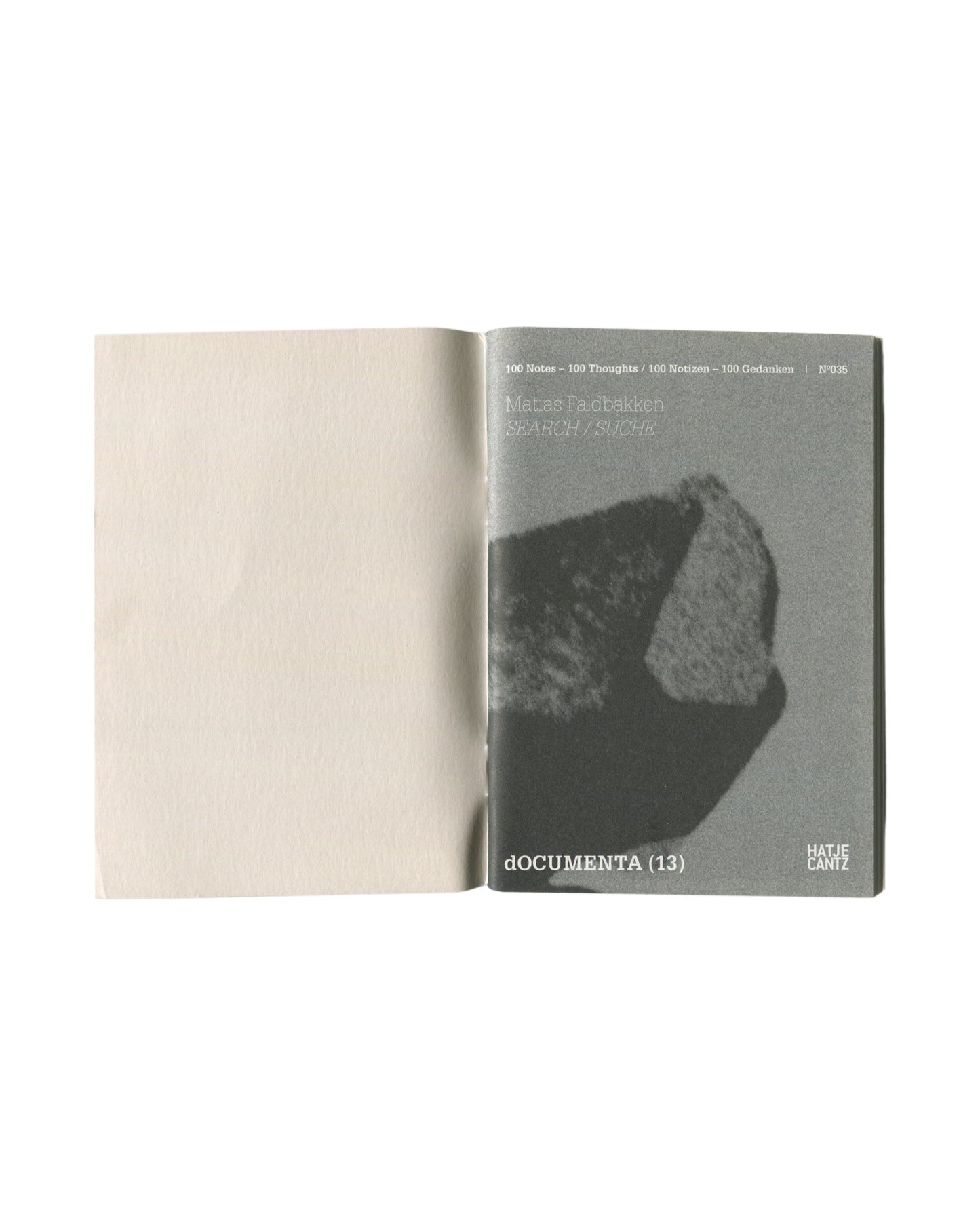 Interior spread showing opening pages with grainy monochrome photograph of a rock or stone fragment as inner cover image, opposite blank page.