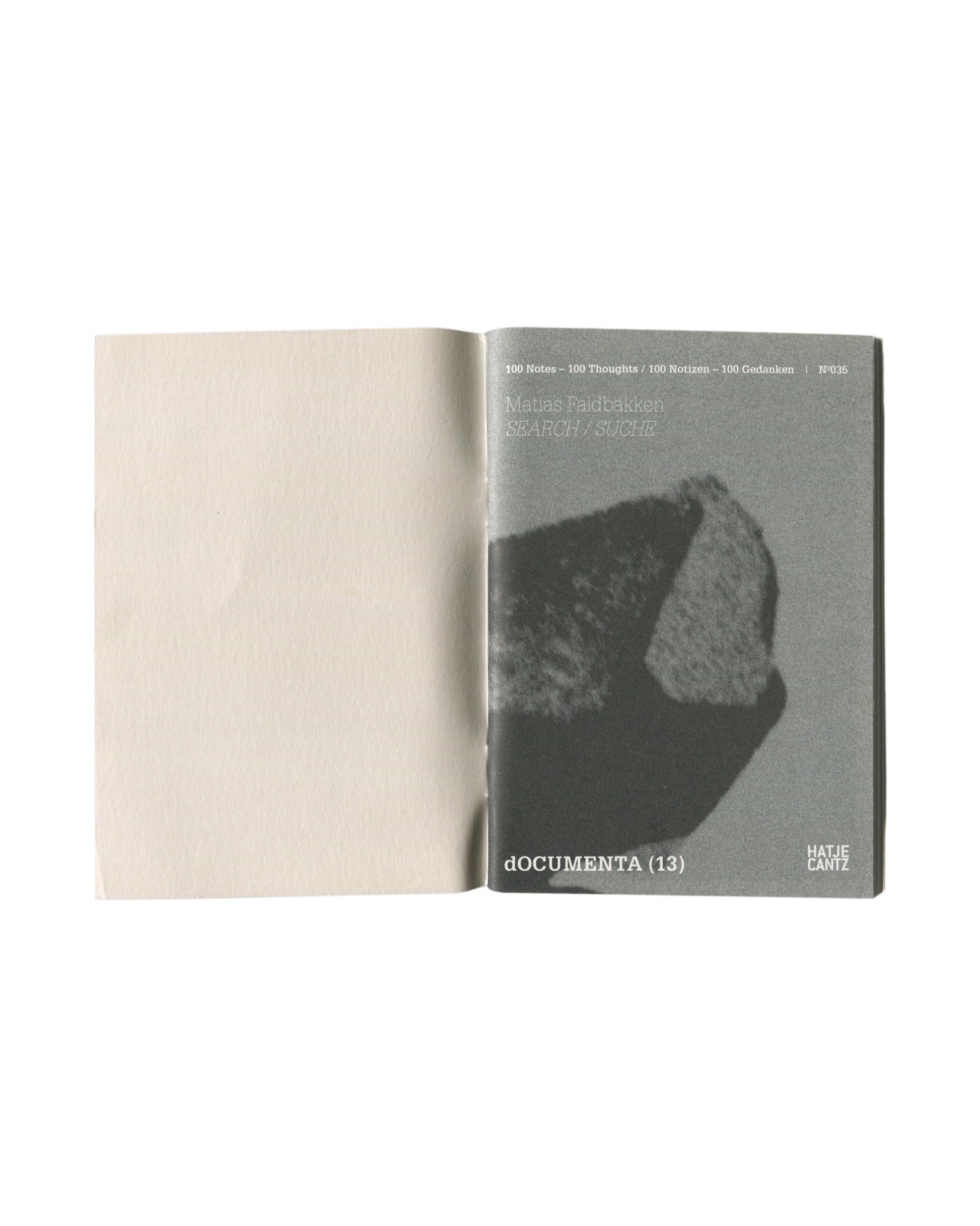 Interior spread showing opening pages with grainy monochrome photograph of a rock or stone fragment as inner cover image, opposite blank page.