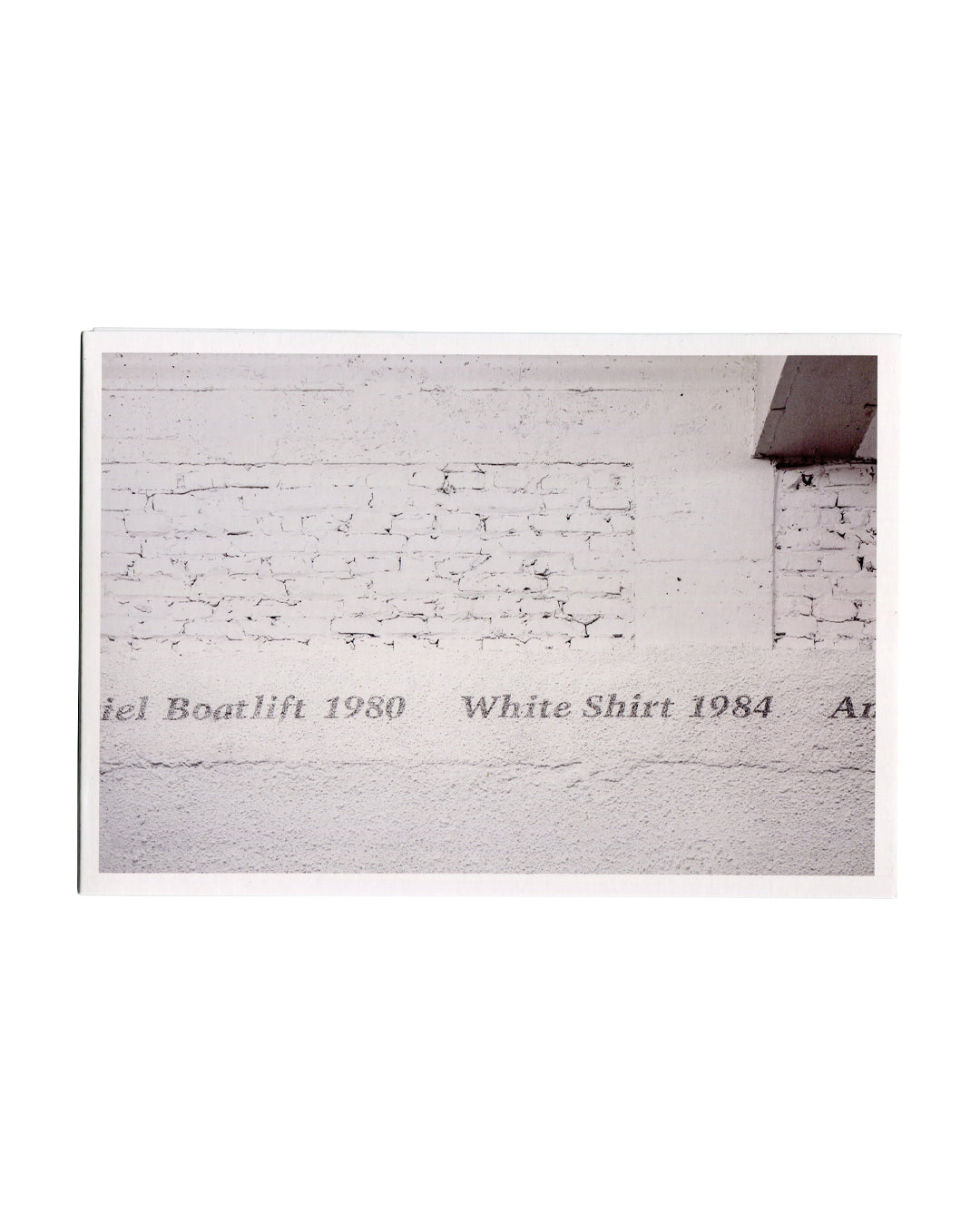 Installation view of Untitled, 1989, paint on wall — text reading Mariel Boatlift 1980, White Shirt 1984 stencilled along the base of a white-painted brick wall.