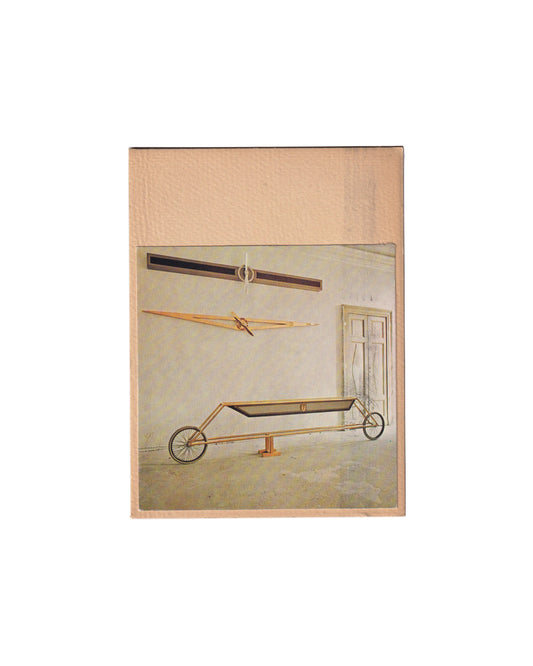 Recto (the front):

Gianni Piacentino, Stampe, Galleria Plura, Milan, 1980. Recto: applied colour photograph of installation view showing three engineered sculptural works — two wall-mounted linear forms and a wheeled floor vehicle — mounted onto cream card stock.