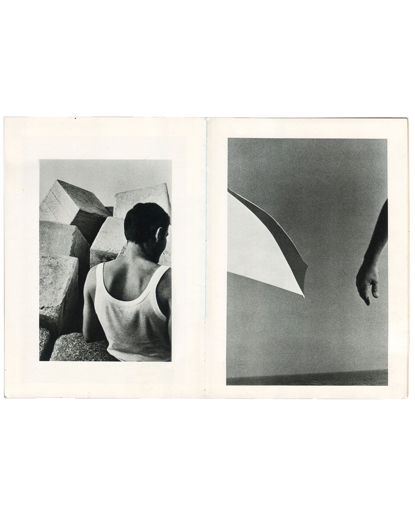  Interior spread of Ralph Gibson, Deja-Vu, Lustrum Press, 1973, left page showing a figure in a white vest seen from behind amid large stone blocks, right page showing a curved architectural form and a hanging hand against a pale sky.