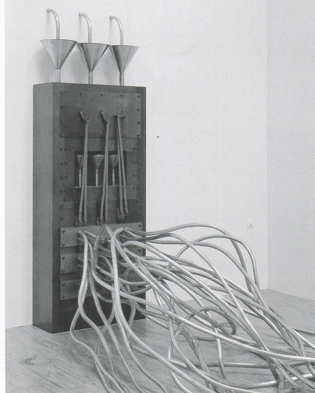Rebecca Horn, Ballet of the Woodpeckers 1986, installation view: tall steel panel with funnel tubes and coiled silver pipes massed on gallery floor