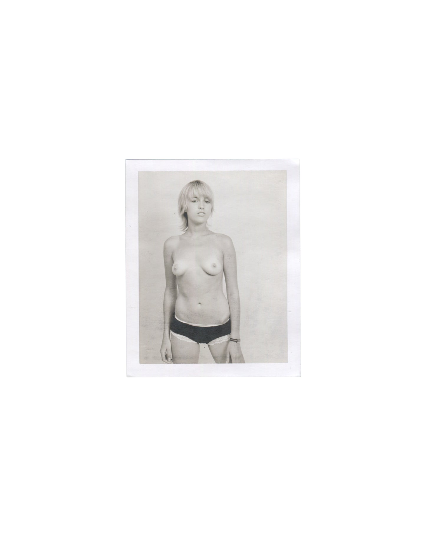 Original Polaroid photograph, Imitation of Christ: A Retrospective, New York, 2002. Black-and-white image of woman with blonde bob, topless in black underwear, slight upward gaze; neutral background; white Polaroid border.