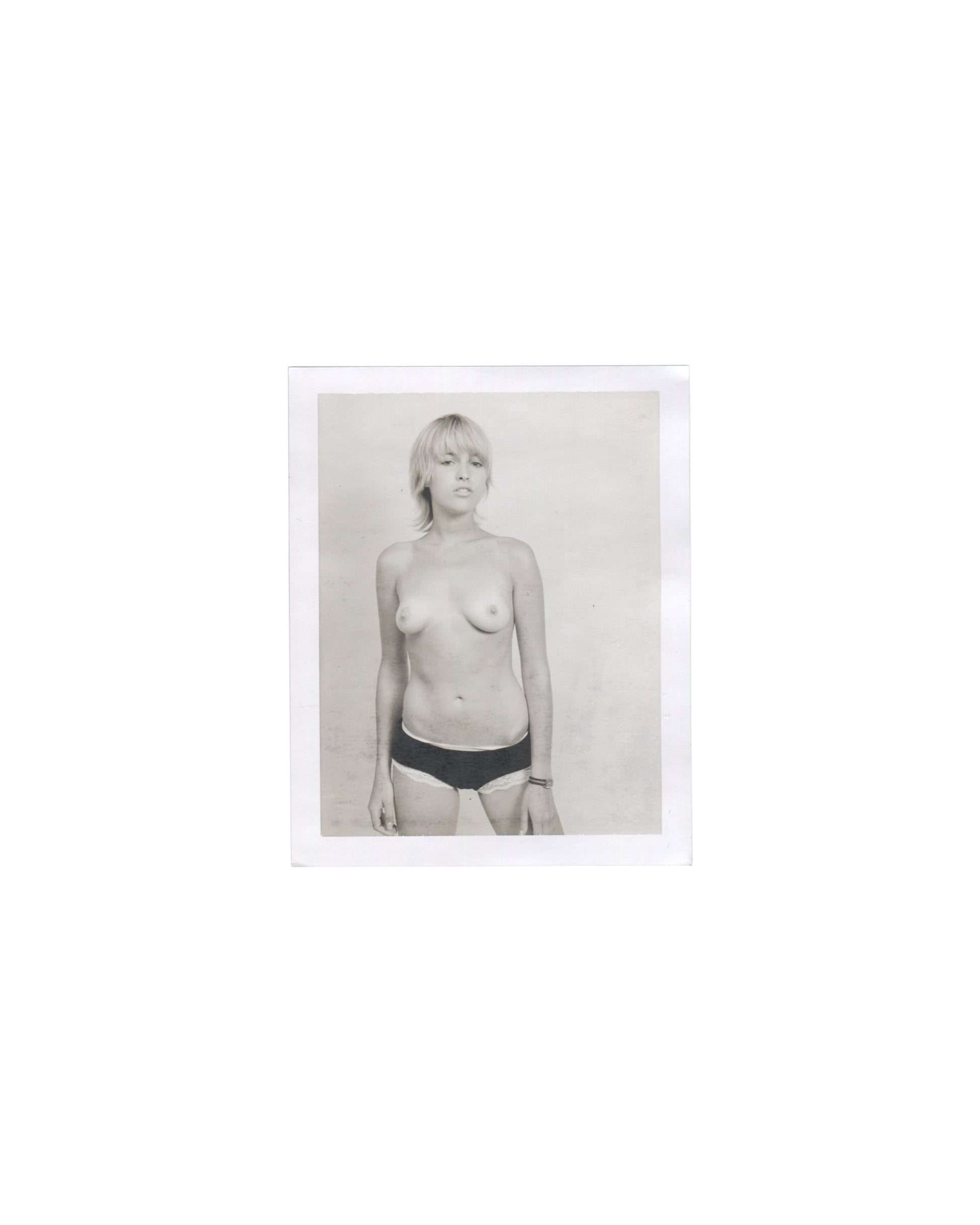 Original Polaroid photograph, Imitation of Christ: A Retrospective, New York, 2002. Black-and-white image of woman with blonde bob, topless in black underwear, slight upward gaze; neutral background; white Polaroid border.