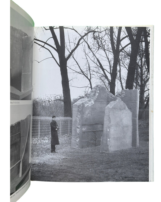 nterior spread: Isa Genzken — 1988 monograph interior, black and white photograph of  a young Isa Genzken standing beside large concrete block sculptures outdoors, bare winter trees