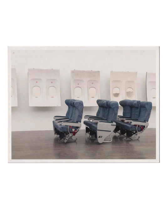 Isa Genzken, Window, exhibition invitation front. Hauser & Wirth, London, 2020. Colour photograph of installation view: three rows of blue economy-class aircraft seats on a dark wood floor, with a row of white airplane window panels mounted on the gallery wall behind. Untitled (detail), 2018. Photo: Todd White Art Photography.