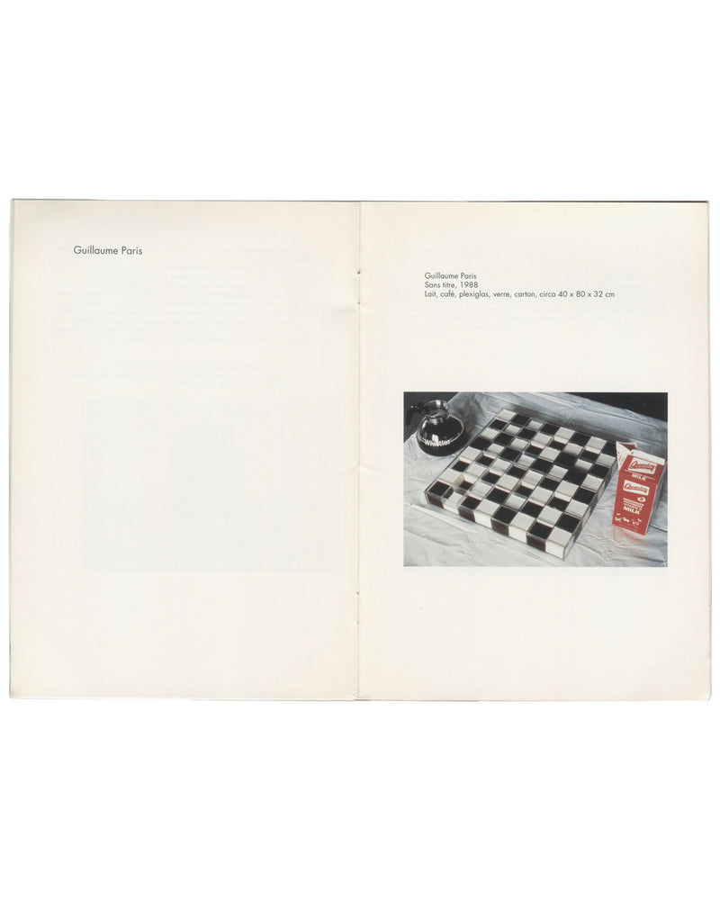 Guillaume Paris — Sans titre, 1988 Exhibition catalogue, Fiasco, Art : Concept, Nice, 1992. Interior spread: Guillaume Paris section. Left page: artist name Guillaume Paris in small serif type. Right page: caption reads Guillaume Paris / Sans titre, 1988 / Lait, café, plexiglas, verre, cotton, circa 40 × 80 × 32 cm. Colour photograph shows a checkerboard grid of alternating black and white squares — a plexiglas tray containing milk and coffee — with a hotel-style service bell and a red Parmalat milk carton