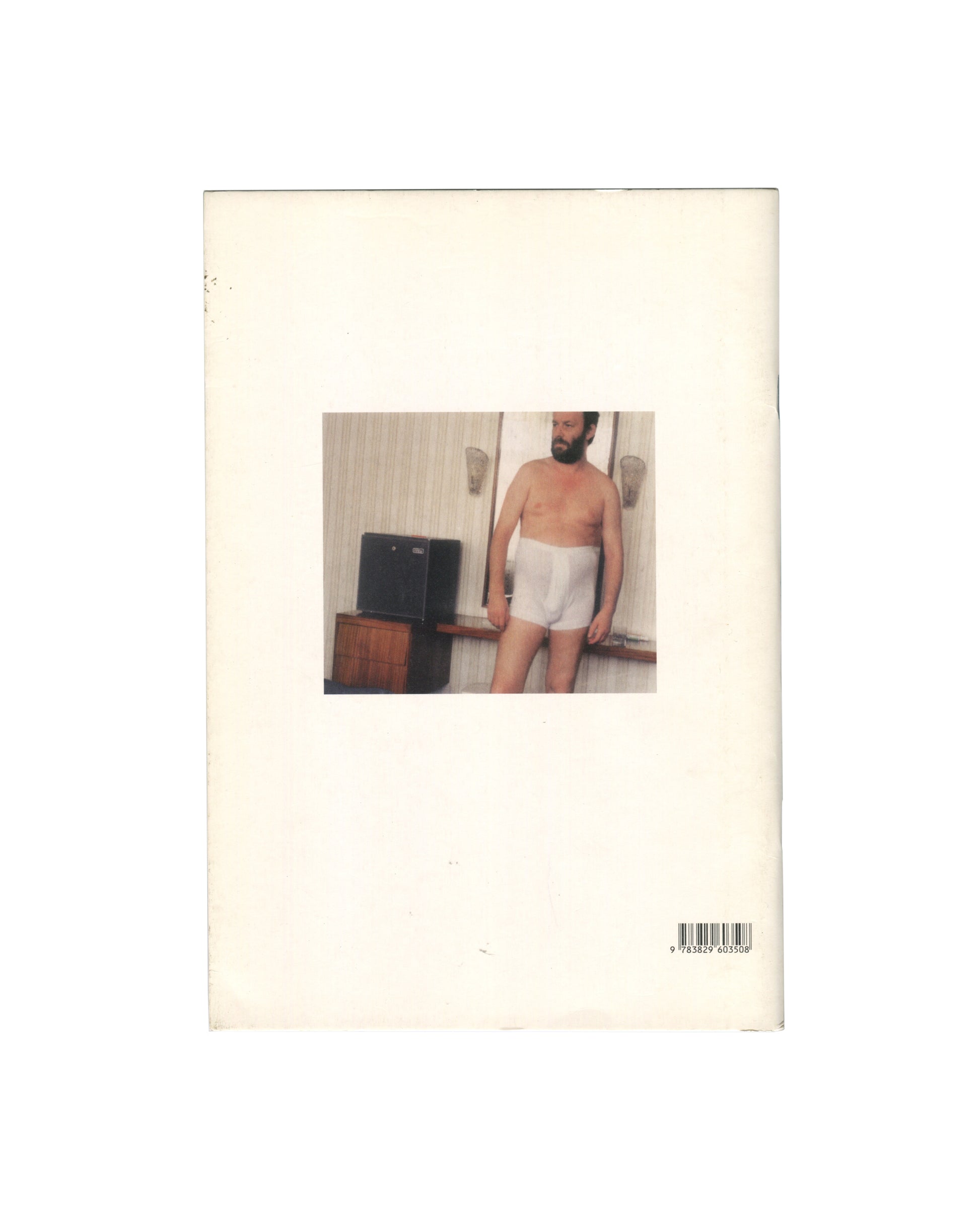 Reverse of 2012 Martin Kippenberger 67 Improved Papertigers Not Afraid of Repetition, Schirmer/Mosel. Back cover showing a colour snapshot photograph of a bearded man in white underwear standing in a hotel room, looking down, with a television and wood-panelled wall behind him. ISBN barcode 9783829603508 lower right. Cream wrappers with handling wear.