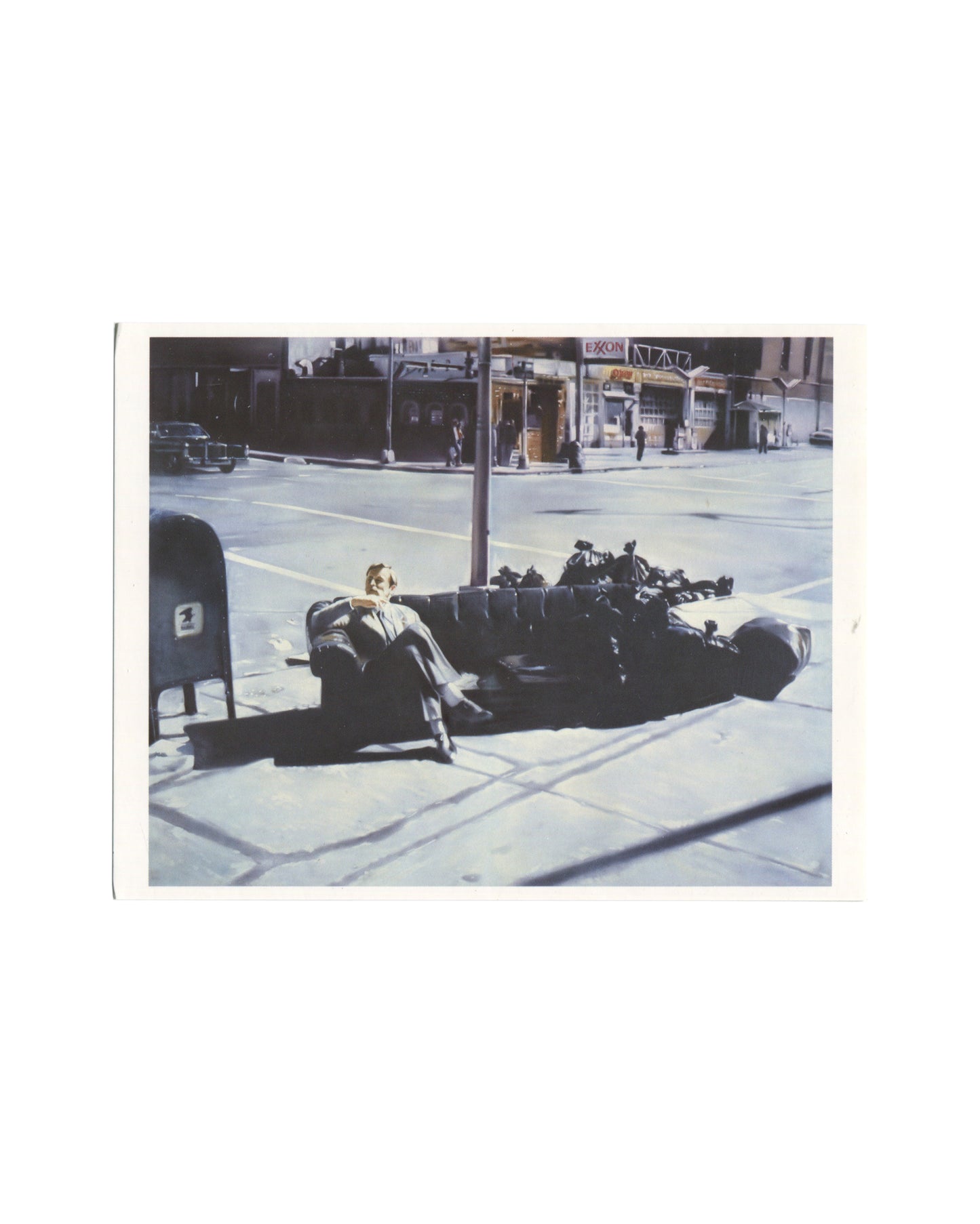 Original 2006 Edition5 artist postcard reproducing Martin Kippenberger's painting Ohne Titel, 1981, from the Lieber Maler, male mir series, showing a colour photorealist painting of a suited man reclining on a dark upholstered sofa abandoned on a city pavement at a wide intersection, a lamp post rising behind him, a US postal mailbox at left, and an Exxon petrol station sign visible across the street in the background, the scene rendered with the flat commercial precision characteristic of the series.