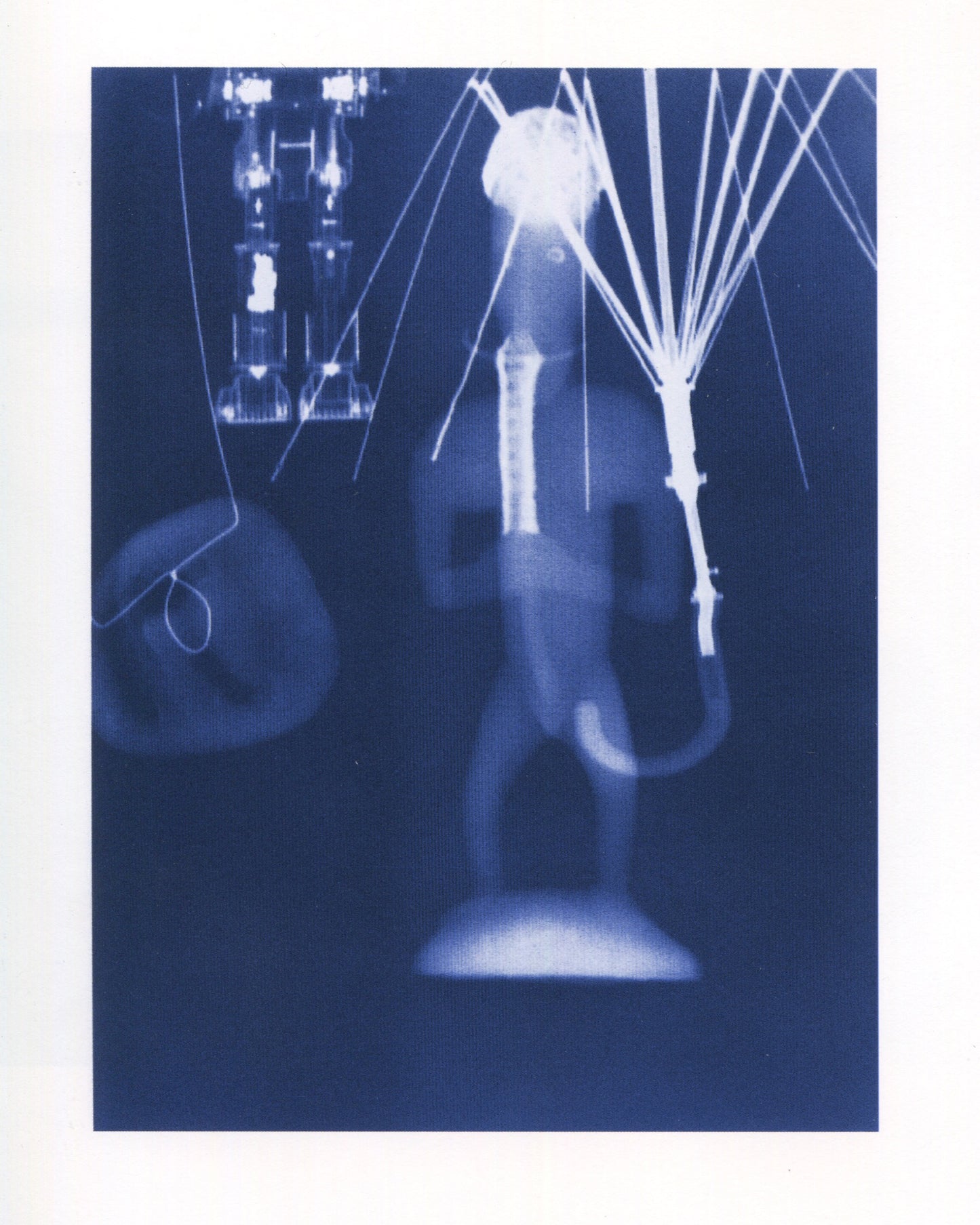 Interior page from Jürgen Klauke Prosecuritas catalogue, 1994. Full-page cyanotype or X-ray image on deep blue ground showing a ghostly still life: a trumpet or horn form at centre, a spherical object with radiating wires upper right, and mechanical or electronic components upper left, all rendered as luminous white forms against the dark blue field.