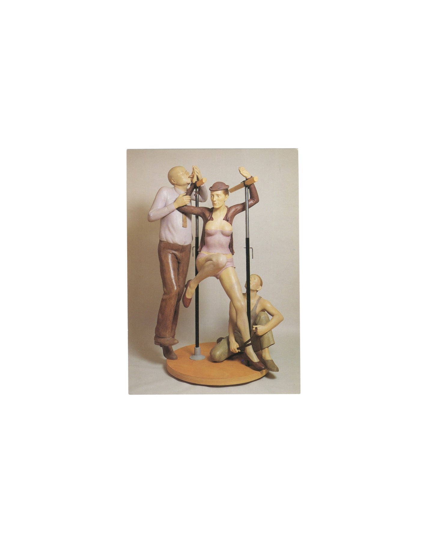 1999 Pierre Klossowski exhibition invitation featuring a color reproduction of *Roberte aux barres parallèles* (1990). Three stylized human figures are arranged around parallel bars on a circular base: a central female figure in pink clothing raises one leg while two surrounding figures engage with the structure. The sculpture is rendered in painted flesh, mauve, and brown tones against a neutral background, with “Pierre Klossowski” printed beneath.