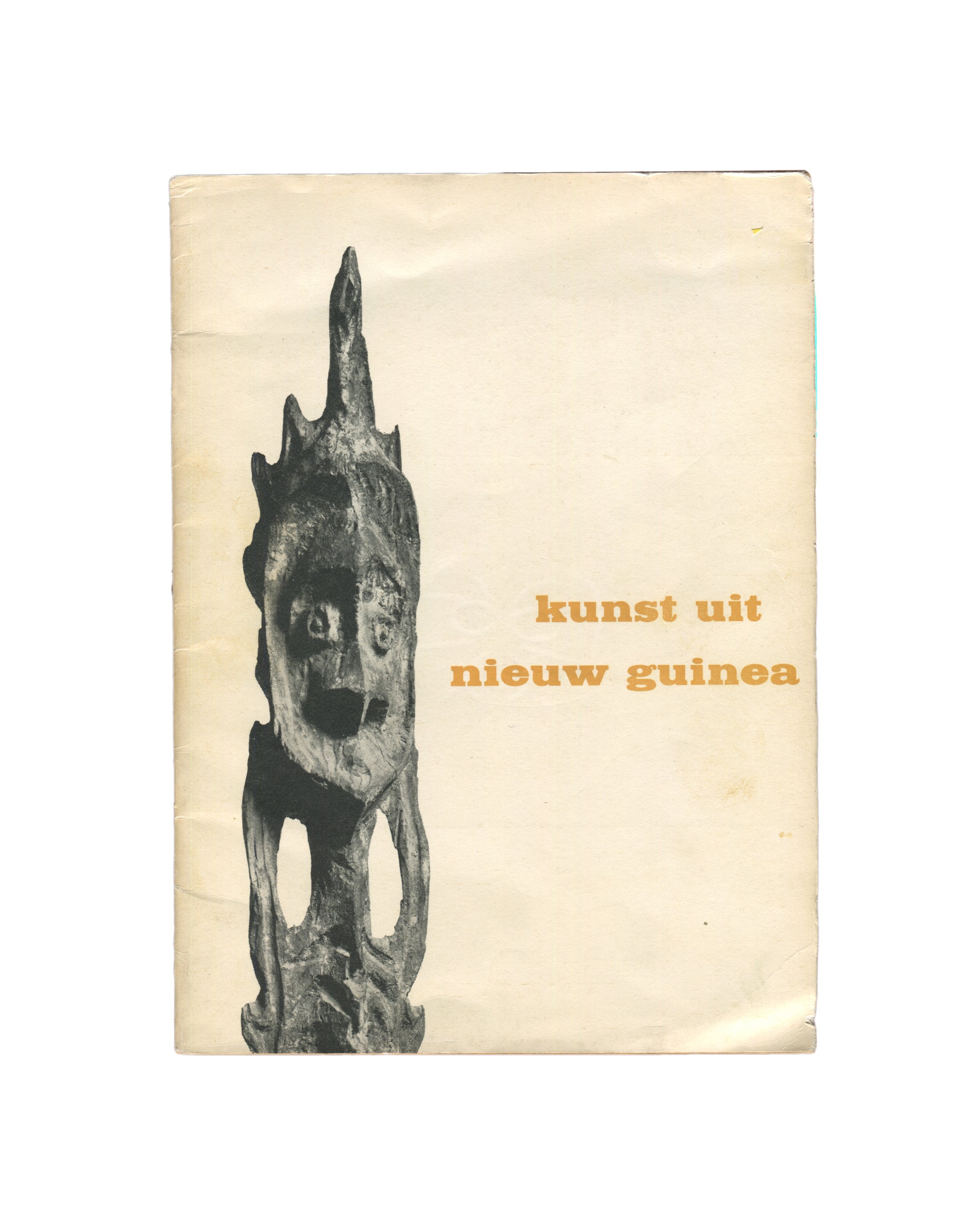 `Kunst uit Nieuw Guinea — exhibition catalogue front cover, 1963. Cream wraps with orange letterpress title lower right: "kunst uit nieuw guinea". Left: black and white photograph of a tall carved wooden ancestor figure (bis pole or similar), with a stylised face, open-work body, and flame-like projections at the crown. Age toning and handling wear throughout.