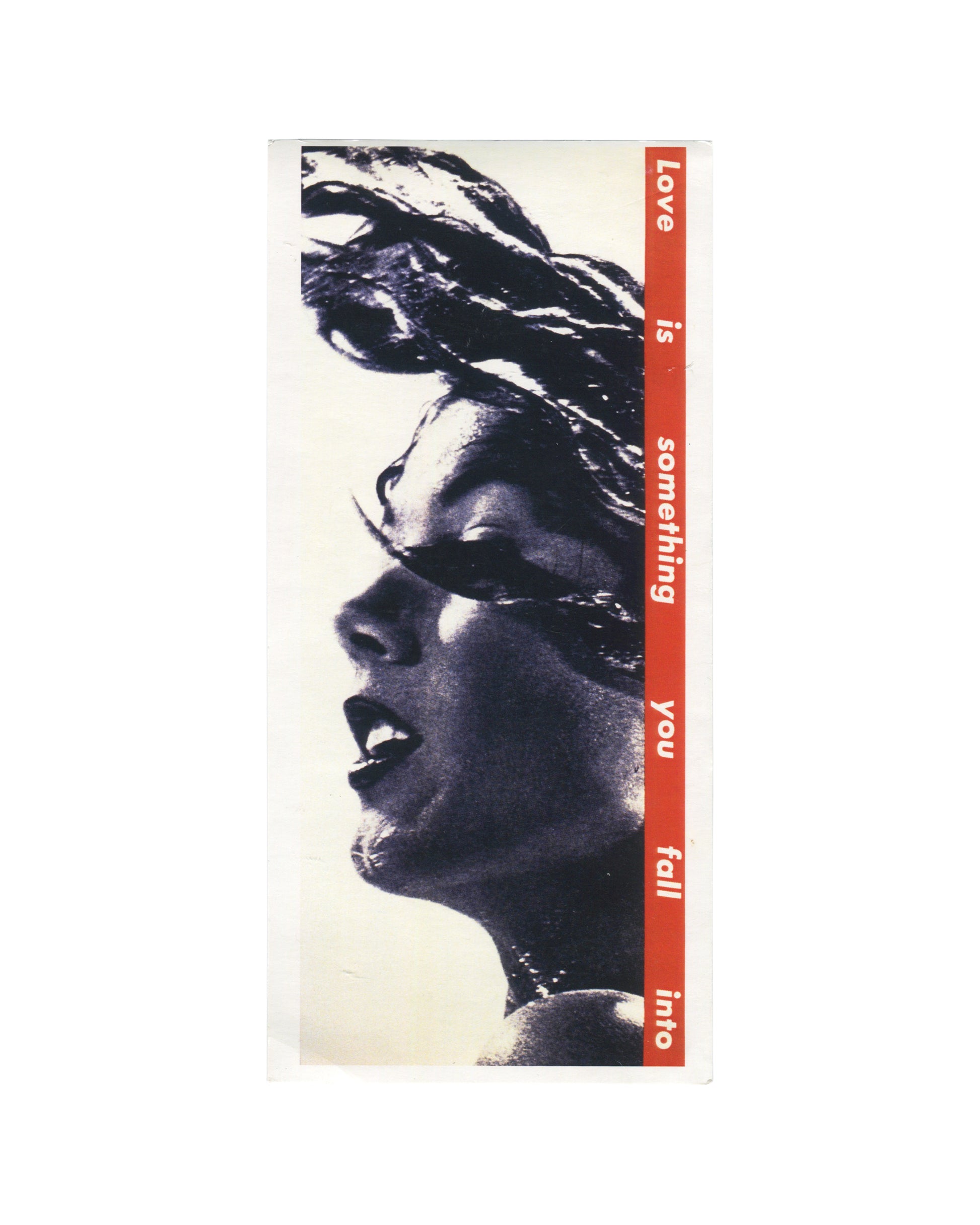 Artist postcard reproducing Barbara Kruger’s Untitled (Love is something you fall into) (1990). A tightly cropped black-and-white profile of a woman with windswept hair fills the card while a vertical red banner runs along the right side with white text reading: “Love is something you fall into
