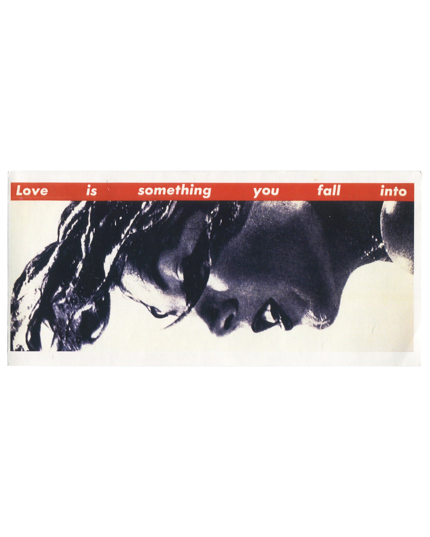 Artist postcard reproducing Barbara Kruger’s Untitled (Love is something you fall into) (1990). A tightly cropped black-and-white profile of a woman with windswept hair fills the card while a vertical red banner runs along the right side with white text reading: “Love is something you fall into