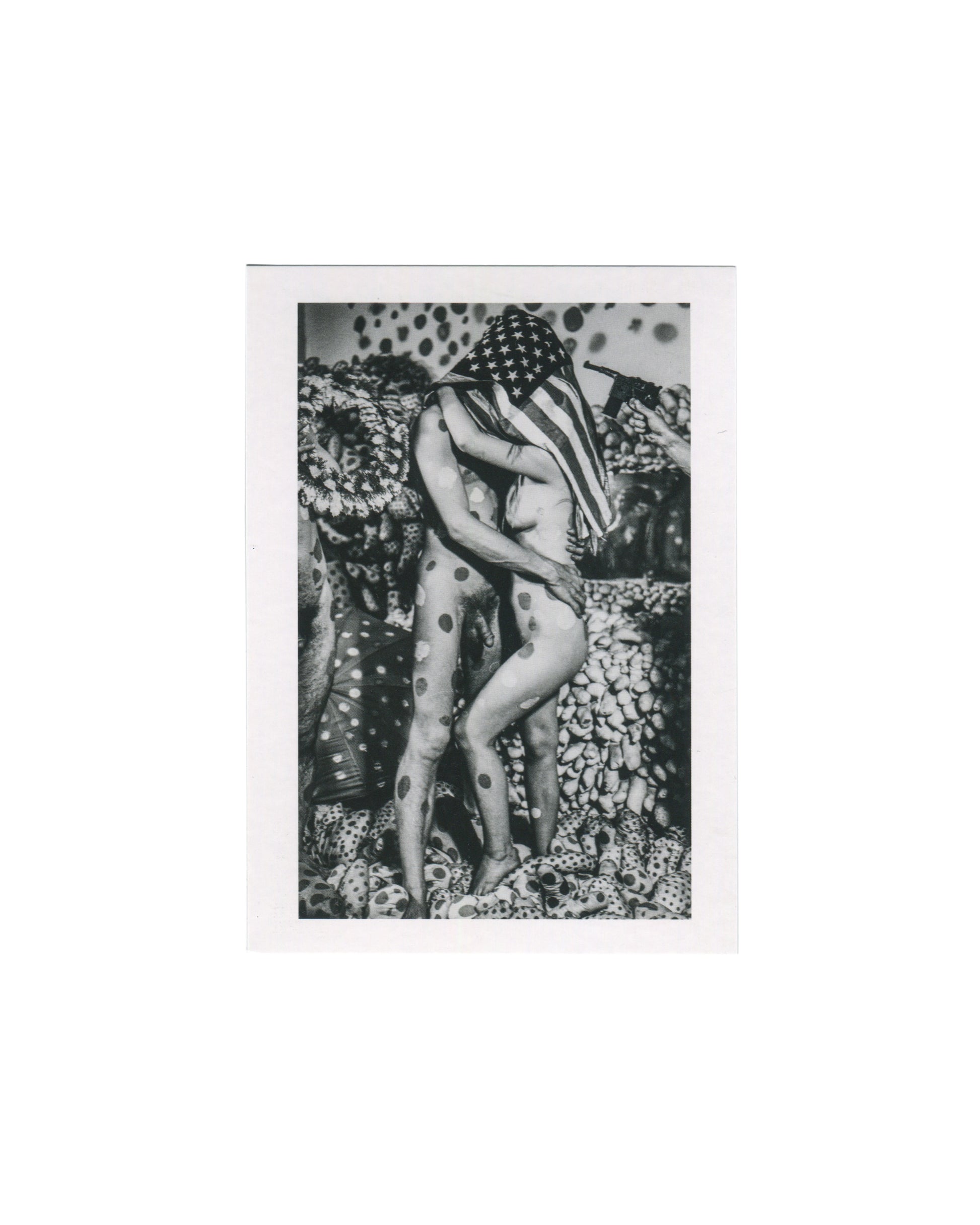 2019 Centre Pompidou exhibition postcard reproducing Harry Shunk and János Kender's black-and-white photograph of Yayoi Kusama's happening Manifestation non identifiée, New York, 1968, showing two nude figures standing and embracing in a dense installation environment of polka-dotted soft sculptures and pumpkin-like forms, one figure's head and upper body draped in an American flag printed with white stars on a dark ground, the other figure's body painted with large dark polka dots, the background filled wi