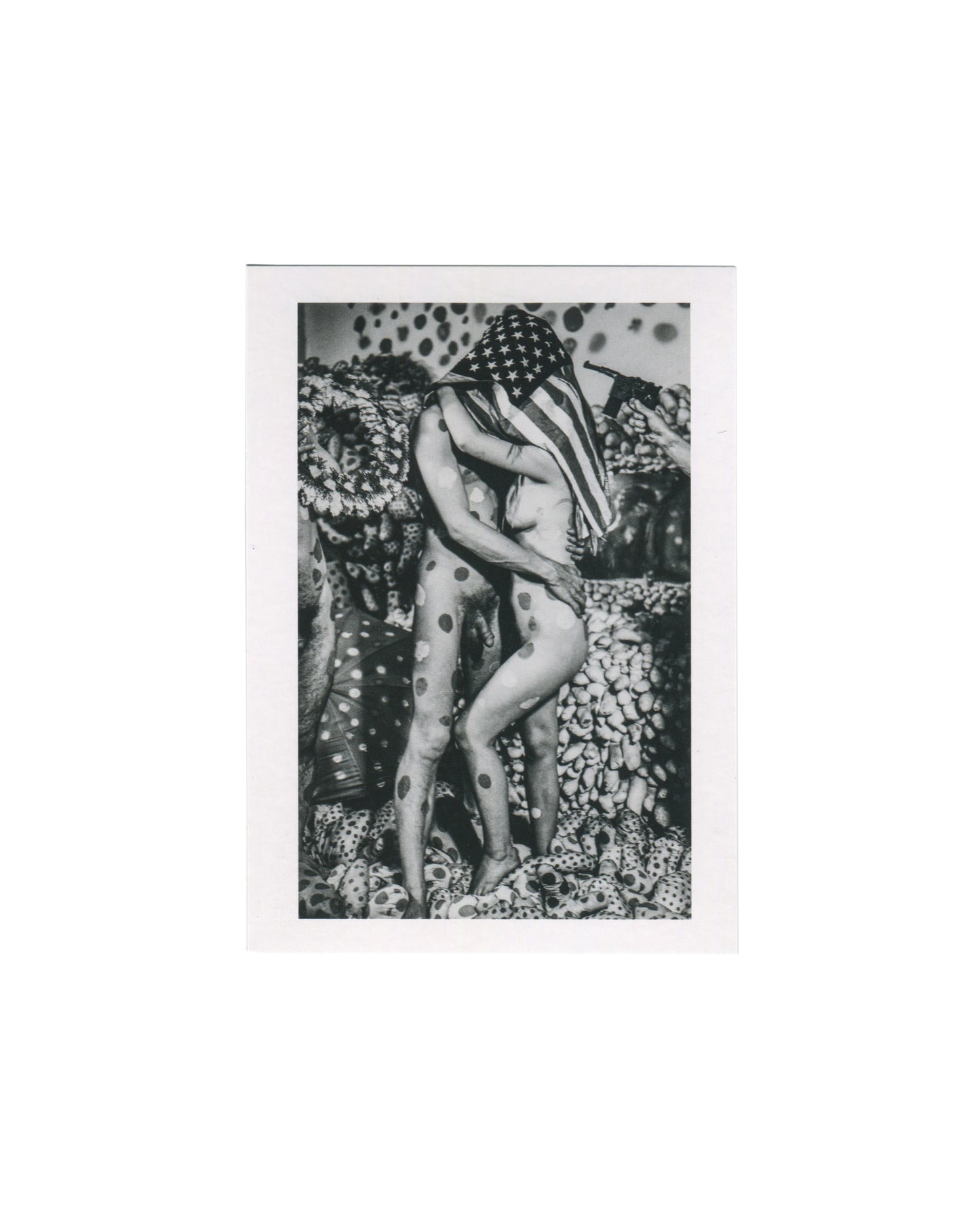 Centre Pompidou postcard reproducing a 1968 black-and-white photograph of two nude performers covered in Yayoi Kusama polka dots embracing beneath an American flag, with a toy gun visible at right and soft-sculpture forms in the background.