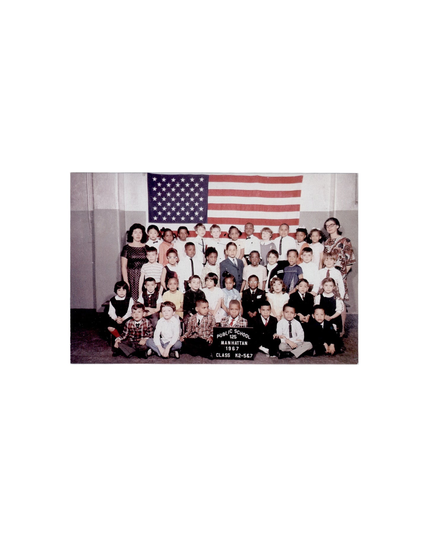 Recto Zoe Leonard, My Kindergarten Class Photo, 2013. Studio Museum in Harlem, Harlem Postcards: Fall/Winter 2013–14. Postcard recto: colour photograph of a school class portrait — Public School 125, Manhattan, 1967, Class K2-567; approximately forty children in four rows with two adult teachers at either side; large American flag on the wall behind; children in formal dress; black placard in the foreground reading 'PUBLIC SCHOOL 125 / MANHATTAN / 1967 / CLASS K2-567'. Warm 1960s colour cast.