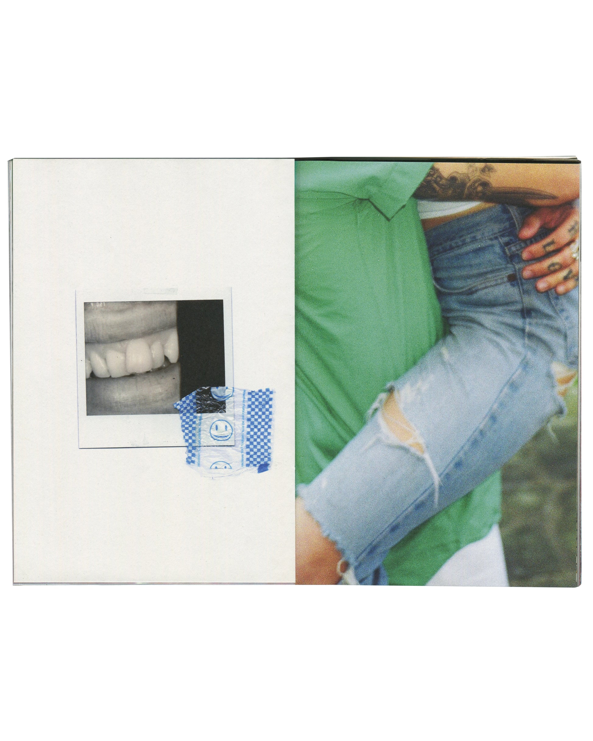  interior spread — left: white page with small Polaroid photograph of teeth/mouth close-up, taped with blue smiley-face washi tape; right: colour photograph, tattooed hand gripping waistband of distressed denim jeans, green shirt