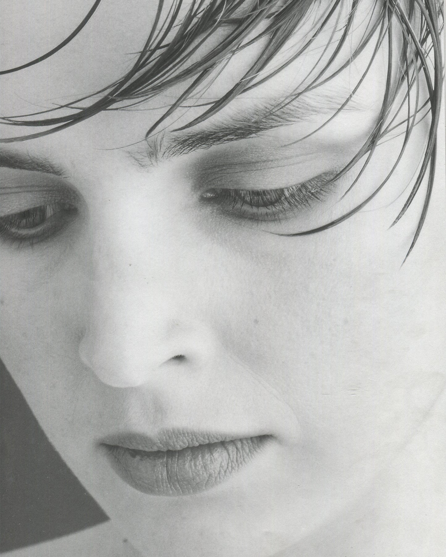 Interior page from Robert Mapplethorpe, Some Women, Bulfinch Press, 1992, showing a black-and-white portrait of a woman in a dark top, her head turned slightly to the right, wearing a small drop earring, her expression composed and direct, against a plain dark background, with the page number visible at lower left.