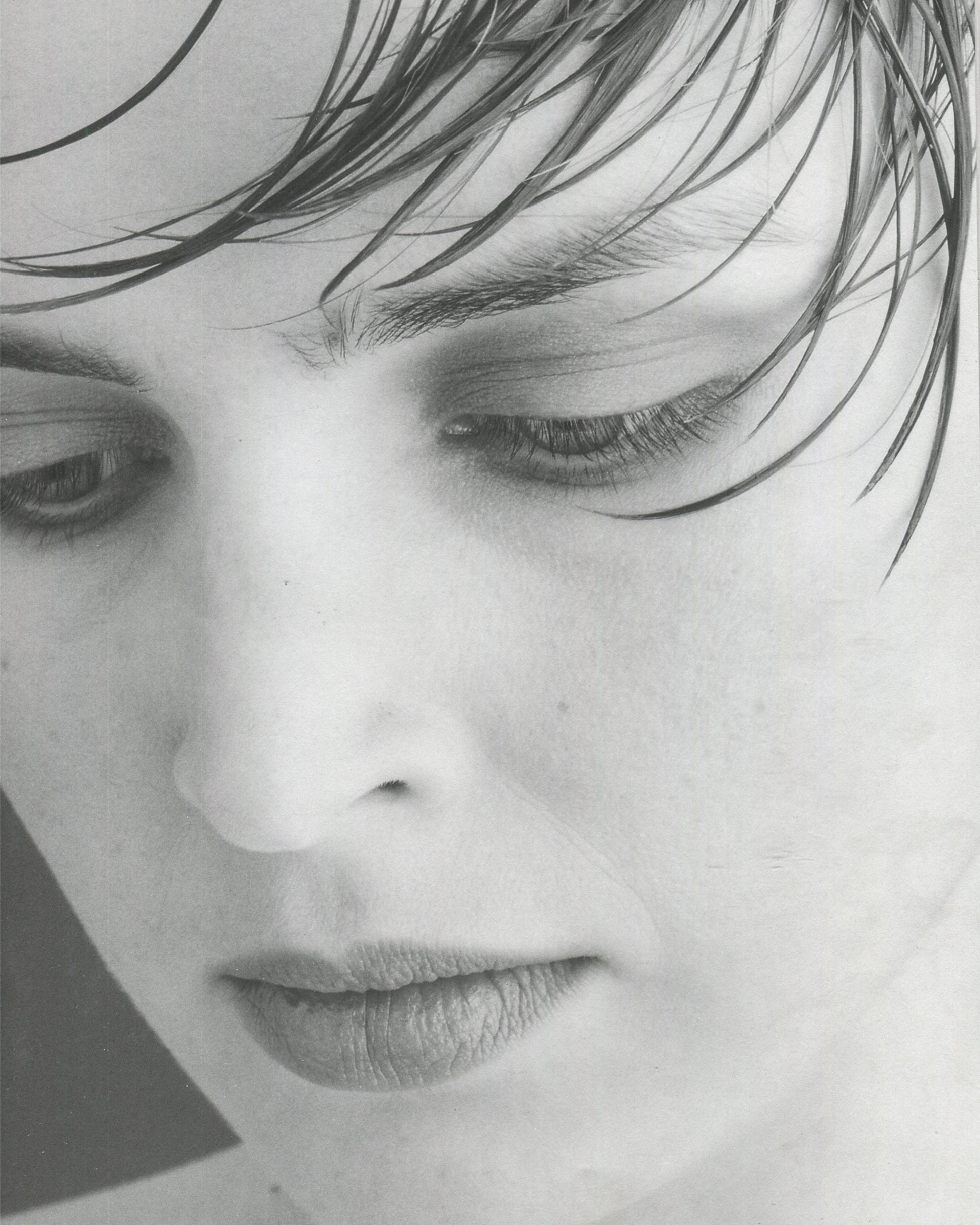 Interior page from Robert Mapplethorpe, Some Women, Bulfinch Press, 1992, showing a black-and-white portrait of a woman in a dark top, her head turned slightly to the right, wearing a small drop earring, her expression composed and direct, against a plain dark background, with the page number visible at lower left.