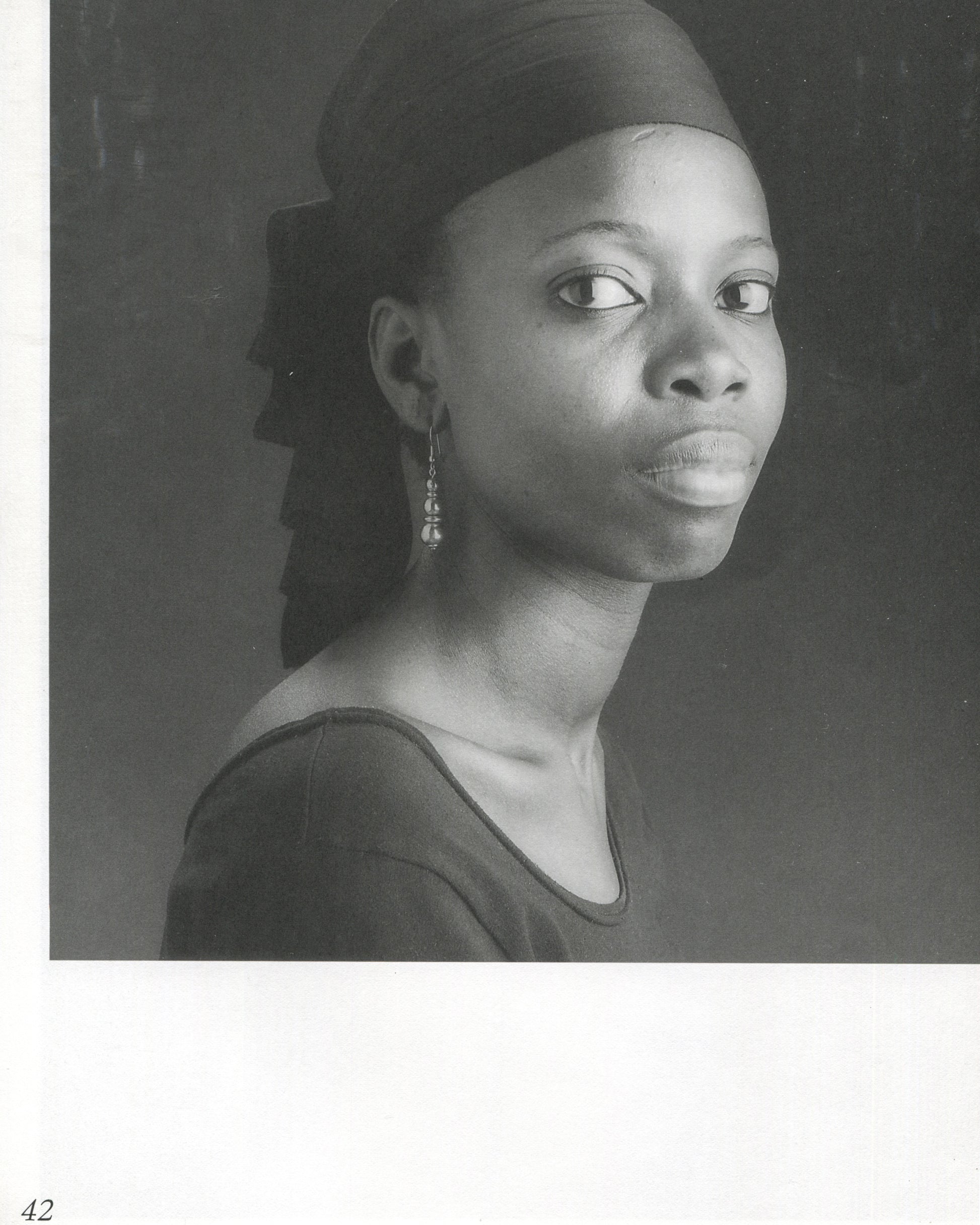 Interior page 42 from Robert Mapplethorpe, Some Women, Bulfinch Press, 1992, showing a black-and-white portrait of a Black woman in three-quarter profile, wearing a dark top and a close-fitting dark head covering with a long tail, a small drop earring visible, her gaze directed slightly upward and to the left, against a dark grey background, page number 42 at lower left.