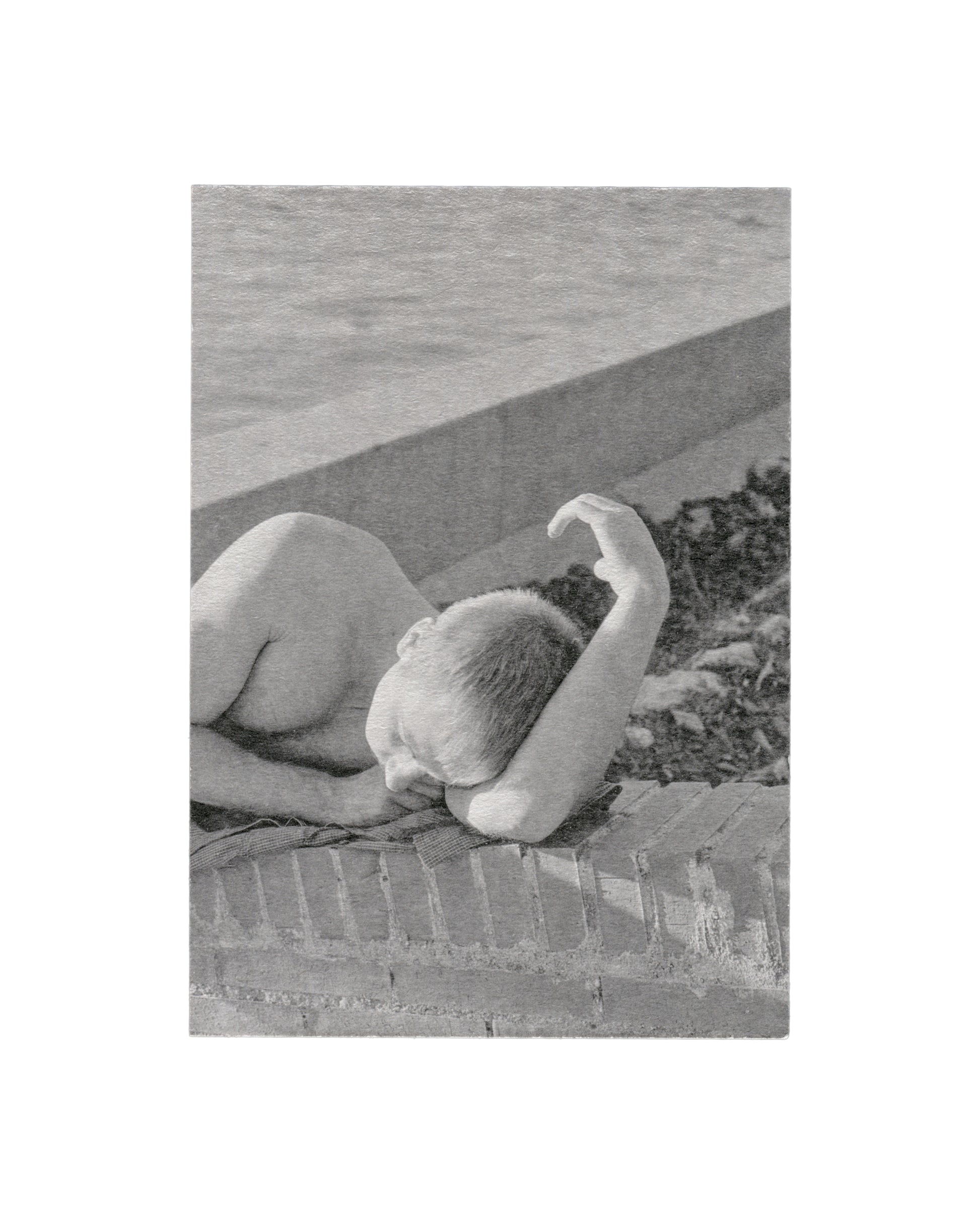 Recto Massao Mascaro, Untitled (Jardin #25), 2016. Galerie C Contemporary Art. Card recto: monochrome photograph on heavily textured card — a nude figure lying face-down on a brick ledge, head turned to one side, one arm raised; concrete surface and dark foliage visible behind; soft diffuse light; high-grain, low-contrast silver gelatin aesthetic.