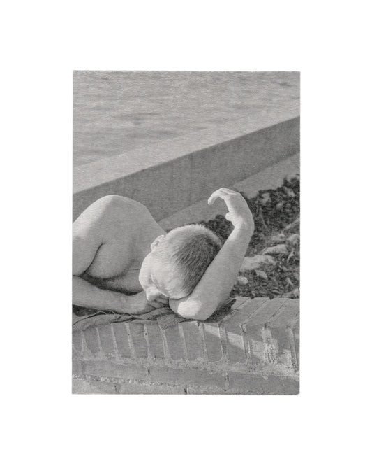 Recto Massao Mascaro, Untitled (Jardin #25), 2016. Galerie C Contemporary Art. Card recto: monochrome photograph on heavily textured card — a nude figure lying face-down on a brick ledge, head turned to one side, one arm raised; concrete surface and dark foliage visible behind; soft diffuse light; high-grain, low-contrast silver gelatin aesthetic.