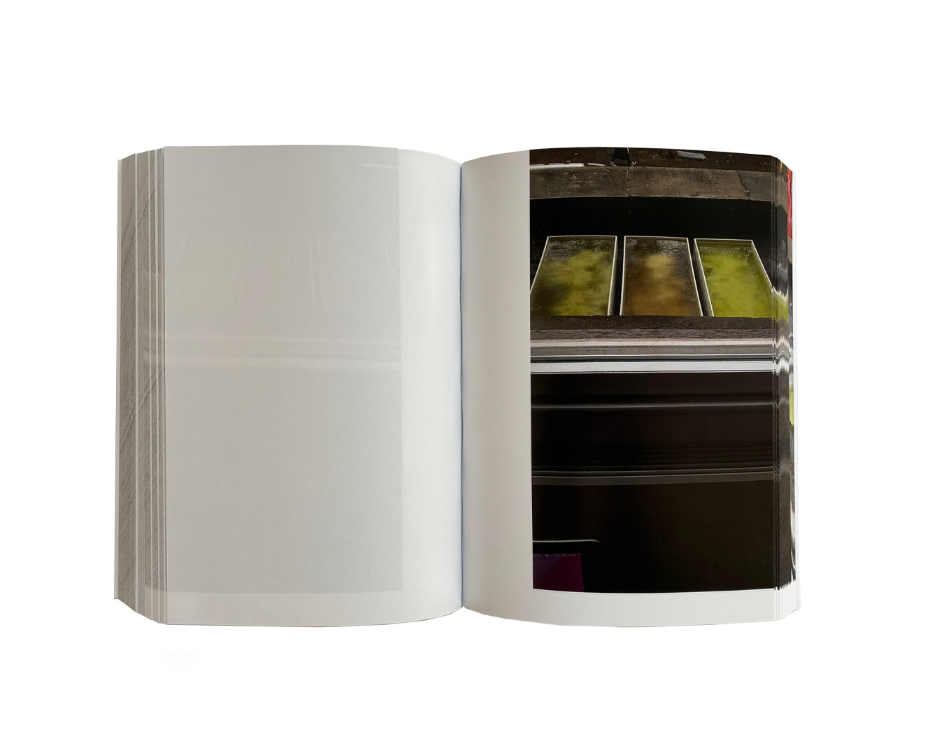 Matthew Peers – Wishing Wells, open spread showing blank left page and full-bleed photograph of three illuminated trays containing green liquid on a dark industrial surface, right page
