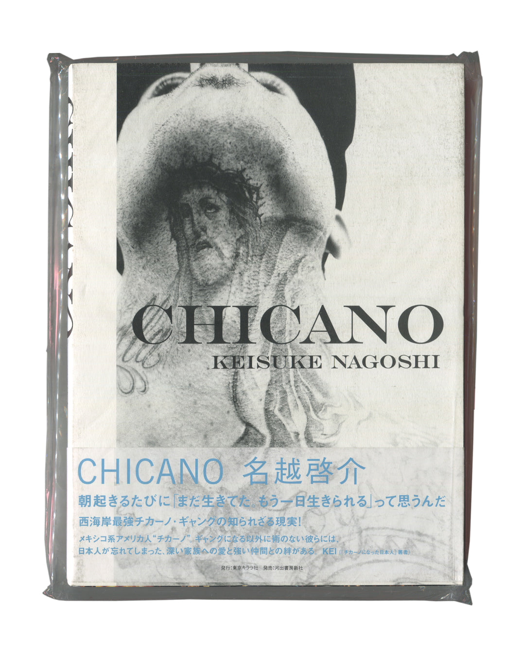 Photobook front cover with obi, Keisuke Nagoshi, CHICANO, Tokyo Kirara-sha / Kawade Shobo Shinsha, Japan, 2008. Sealed in original distributor shrinkwrap. Full-bleed black-and-white photograph — close-up of heavily tattooed torso and neck, head tilted back; dense religious and figurative tattoo imagery including a face, hands, and decorative motifs covering the skin. Bold black serif title 'CHICANO' and 'KEISUKE NAGOSHI' centred over image. Lower third: wraparound obi in white with cyan Japanese text — 